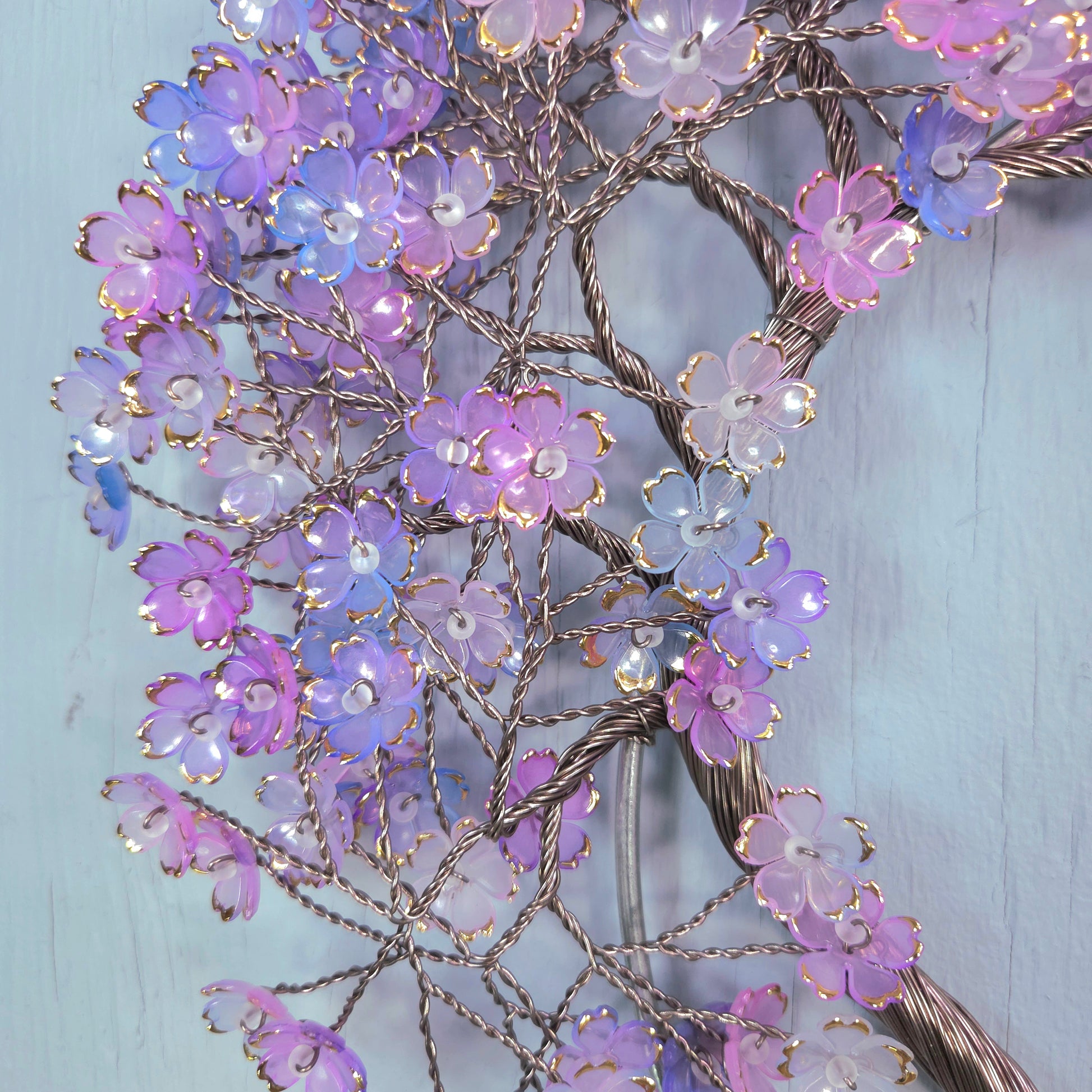Decorative floral branch with purple and pink flowers on a light blue background