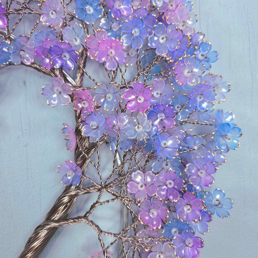 Decorative branch with purple and blue flowers on a light blue background