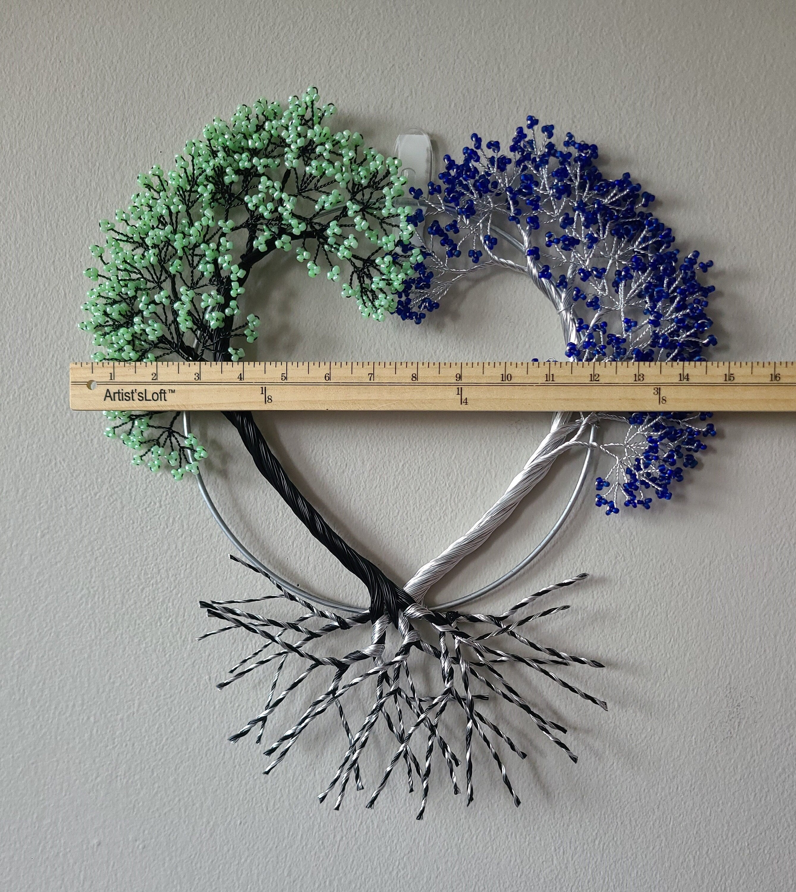 Decorative wall art with heart shape, green and blue elements, and a ruler for scale on a plain background.