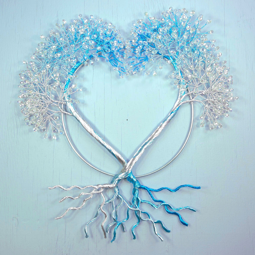 Heart-shaped metal sculpture with blue and silver branches on a light blue background