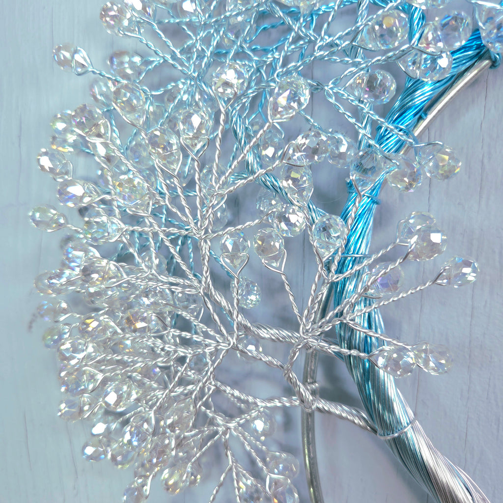 Decorative branch with crystal-like beads on a light wooden background