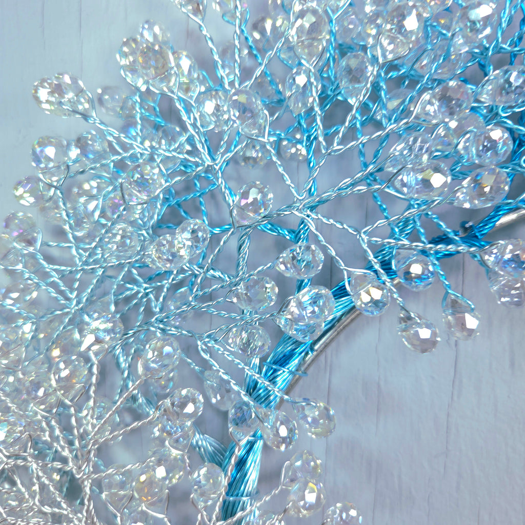 Decorative branch with blue and clear beads on a light wooden background