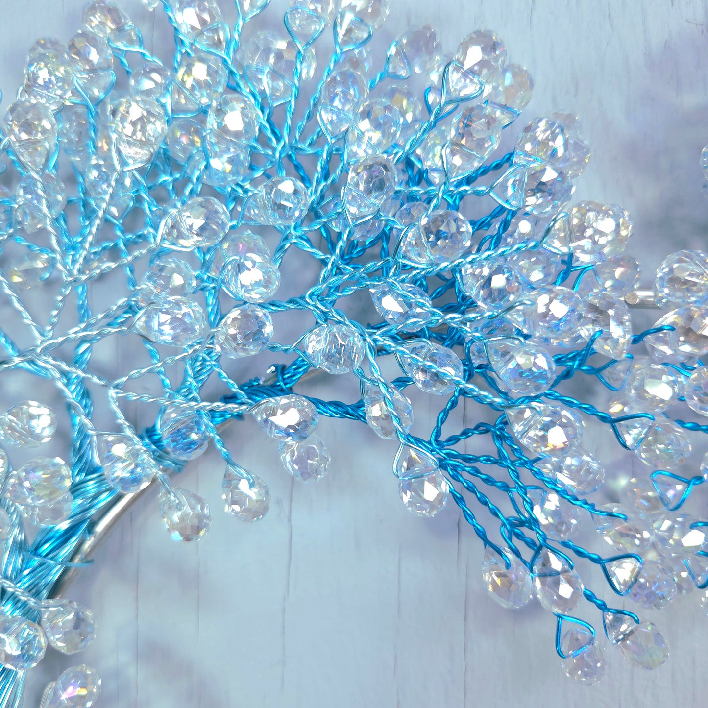 Decorative branch with blue and clear beads on a light wooden background