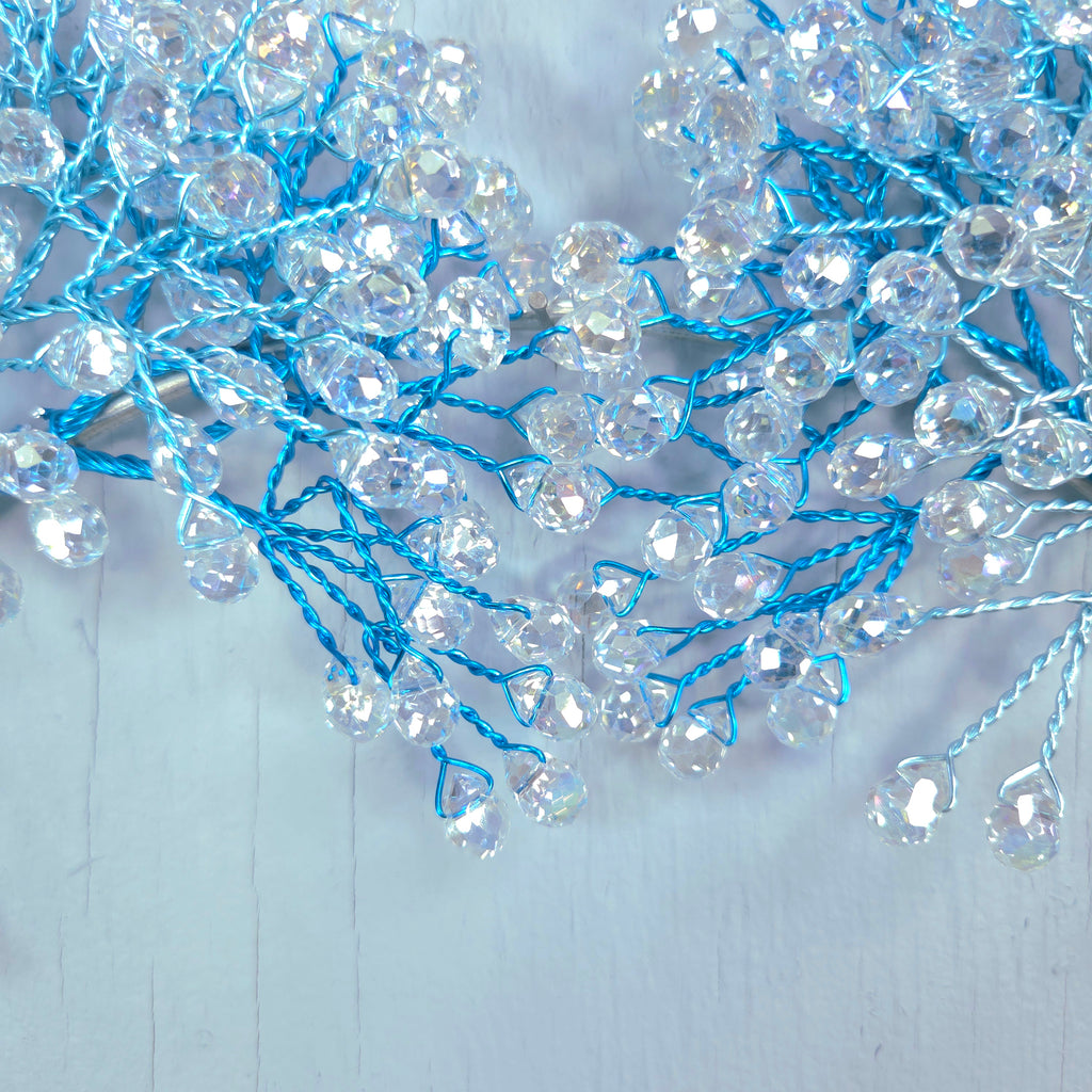 Decorative string with clear beads and blue threads on a light gray background