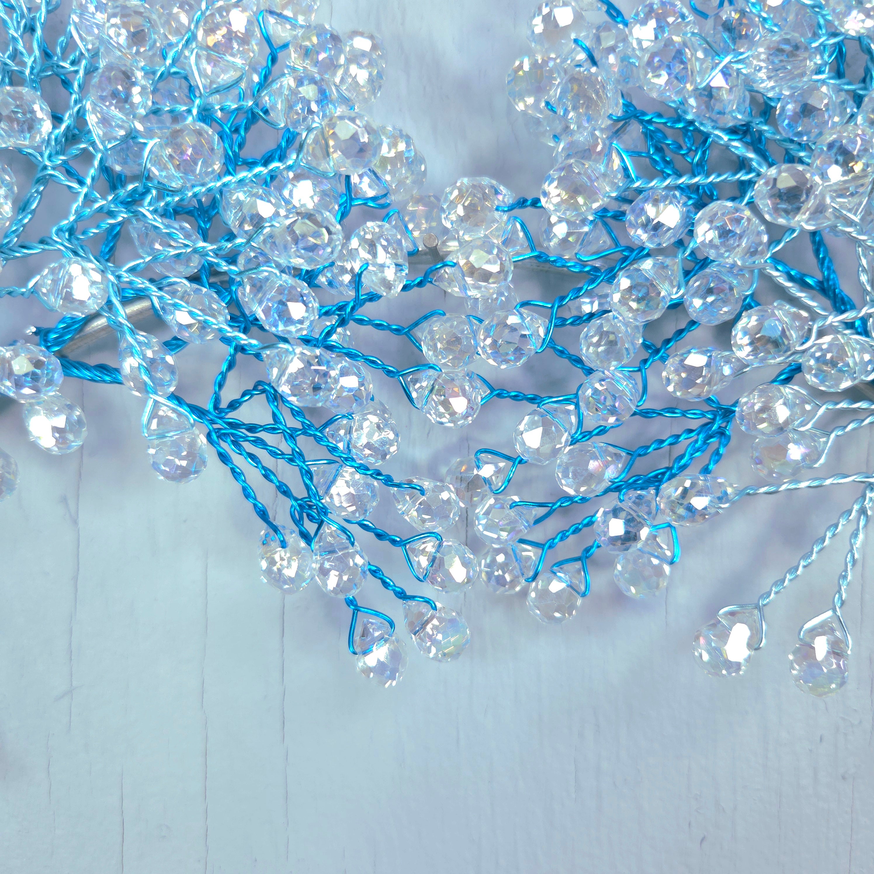 Decorative string with clear beads and blue threads on a light gray background
