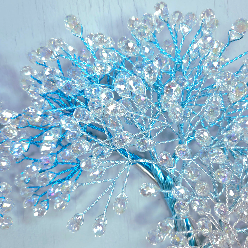 Decorative branch with blue and clear beads on a light background