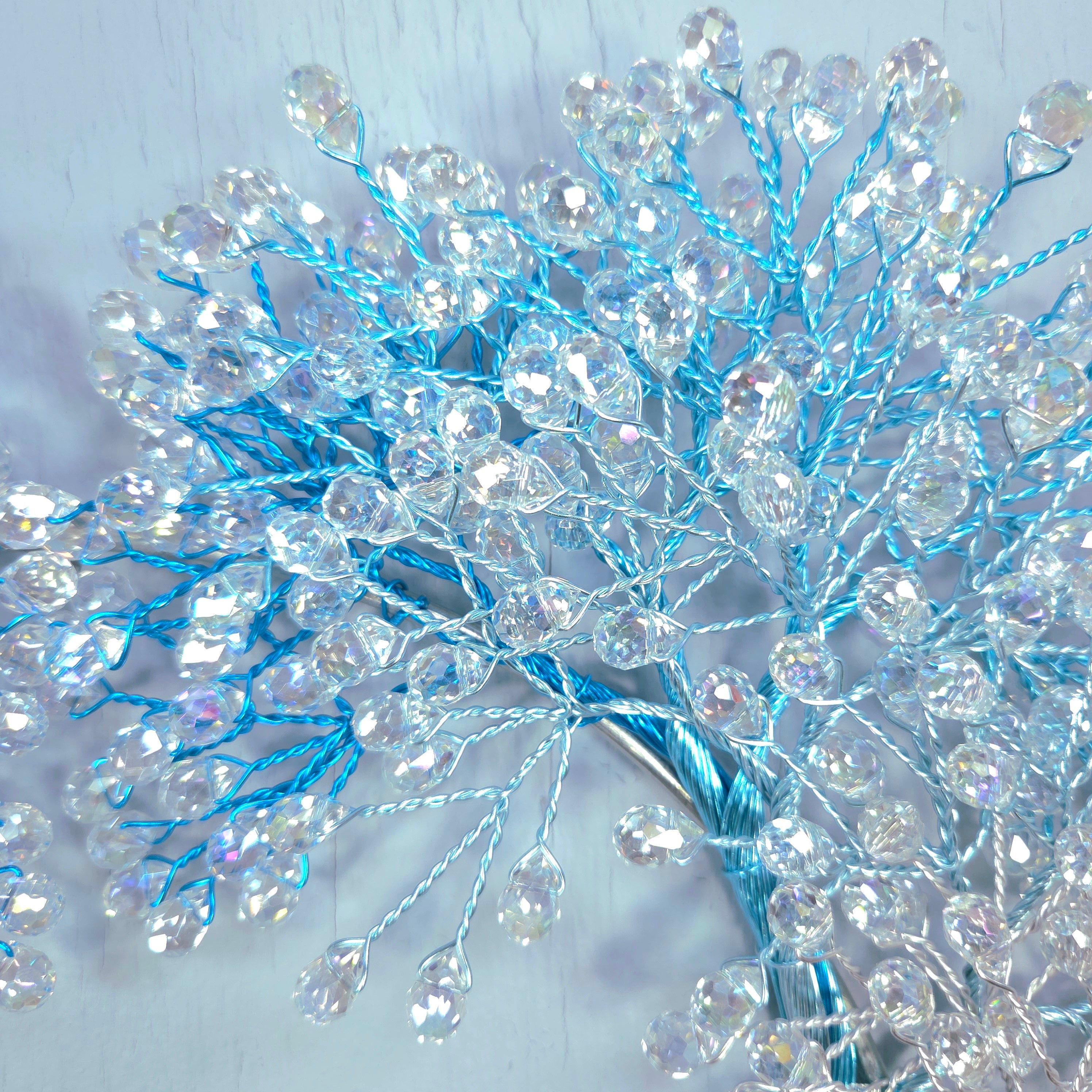 Decorative branch with blue and clear beads on a light background