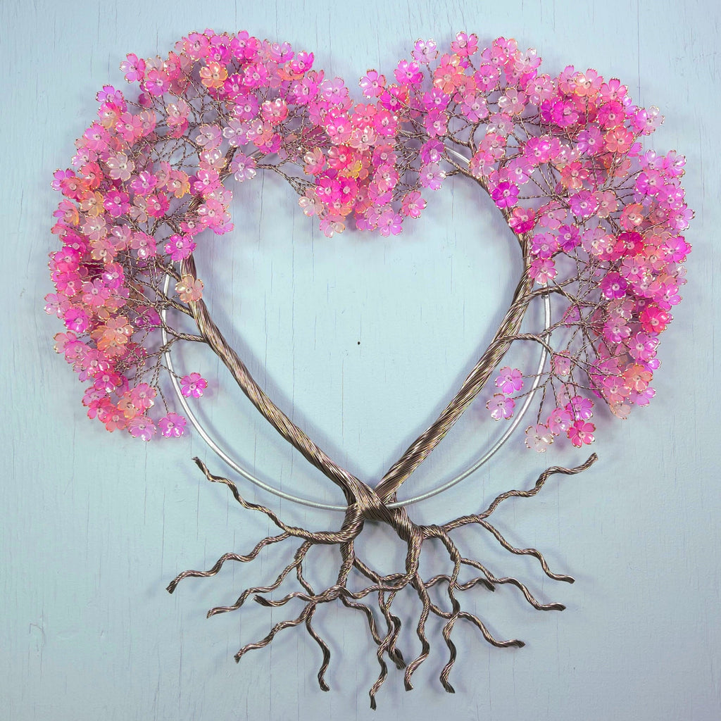 Decorative wall art with pink floral branches and root-like base on a light blue background