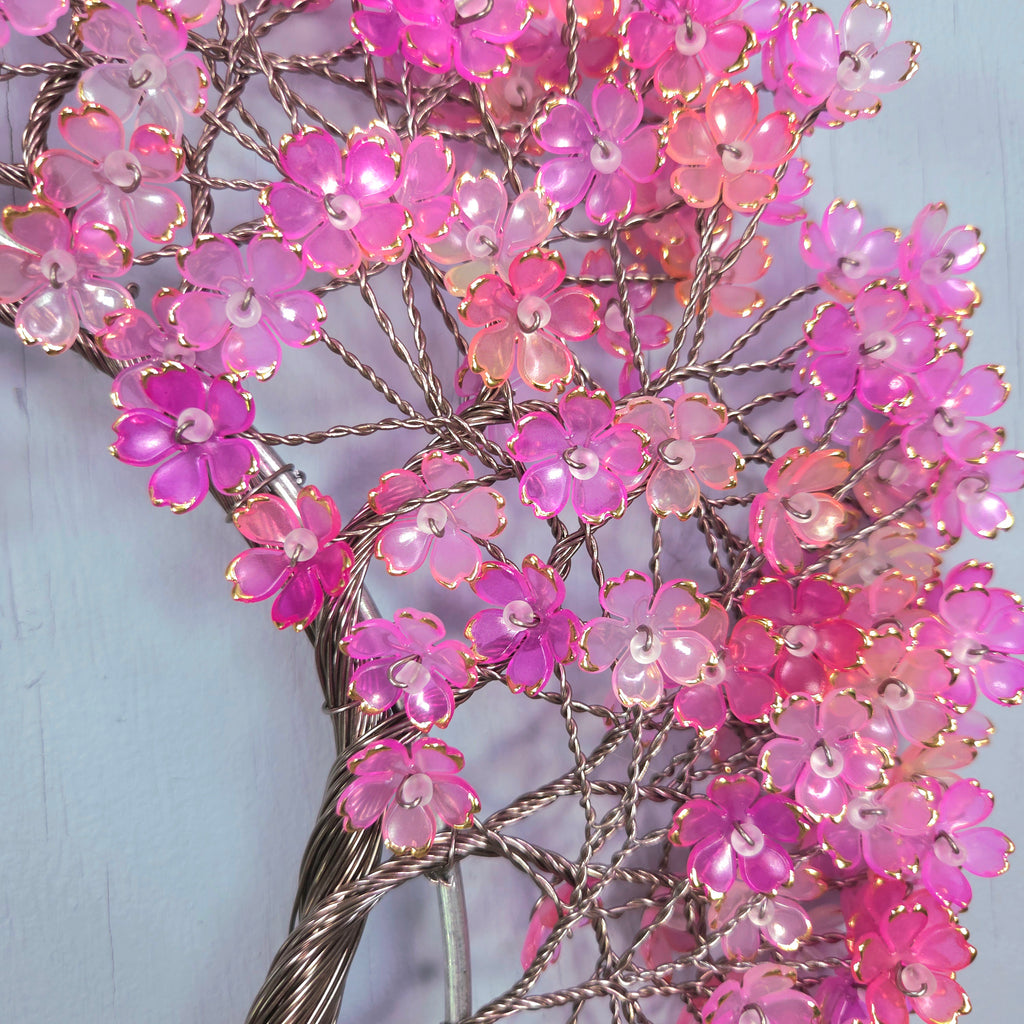 Decorative branch with pink flowers and lights against a light blue background