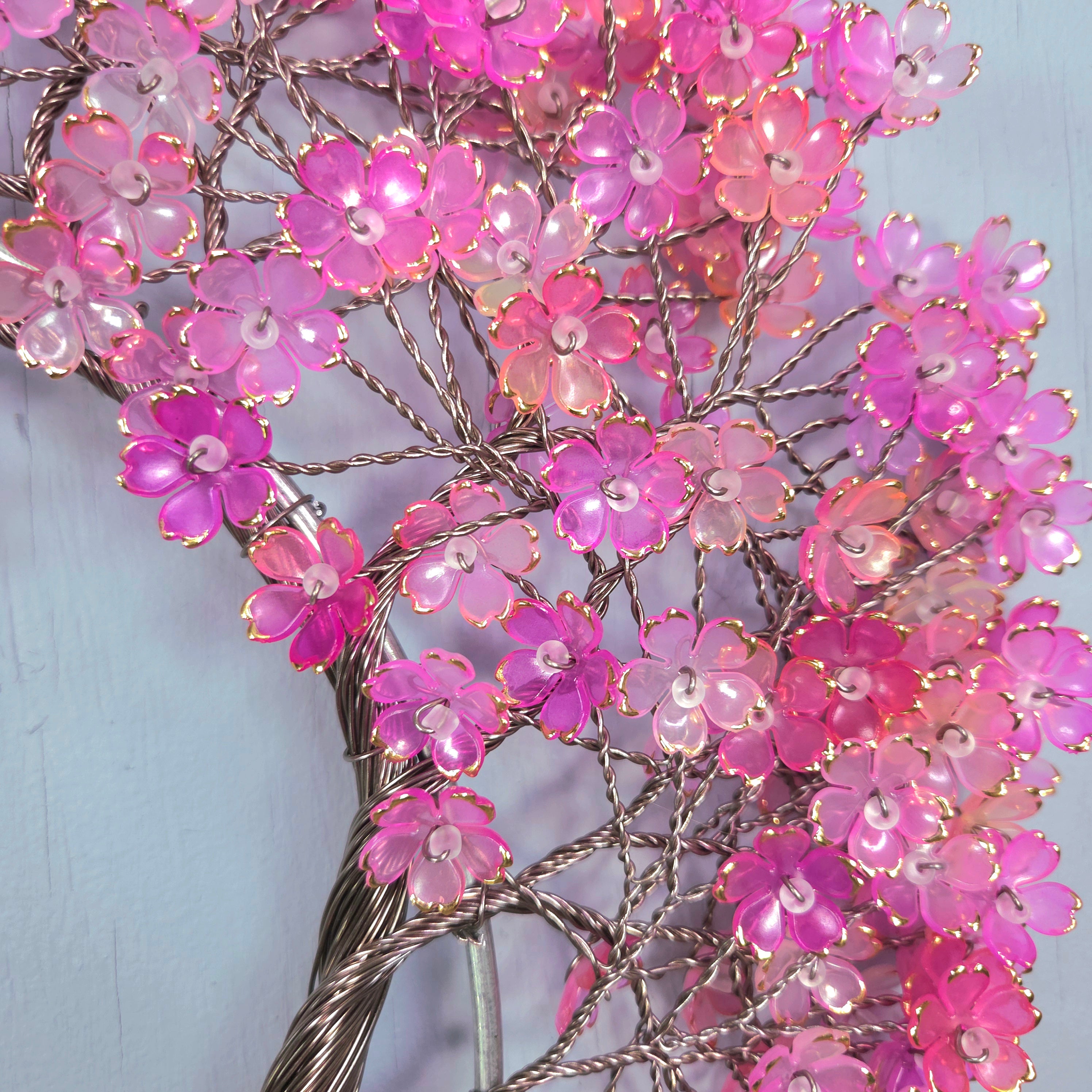 Decorative branch with pink flowers and lights against a light blue background