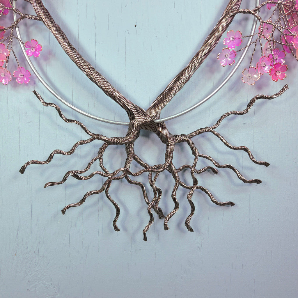 Decorative wall art with twisted metal design and pink flowers on a light blue background
