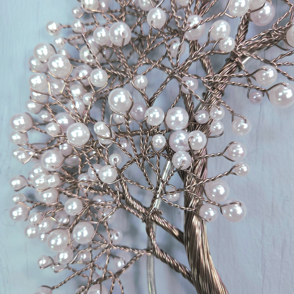 Decorative tree made of branches and pearls on a light blue background