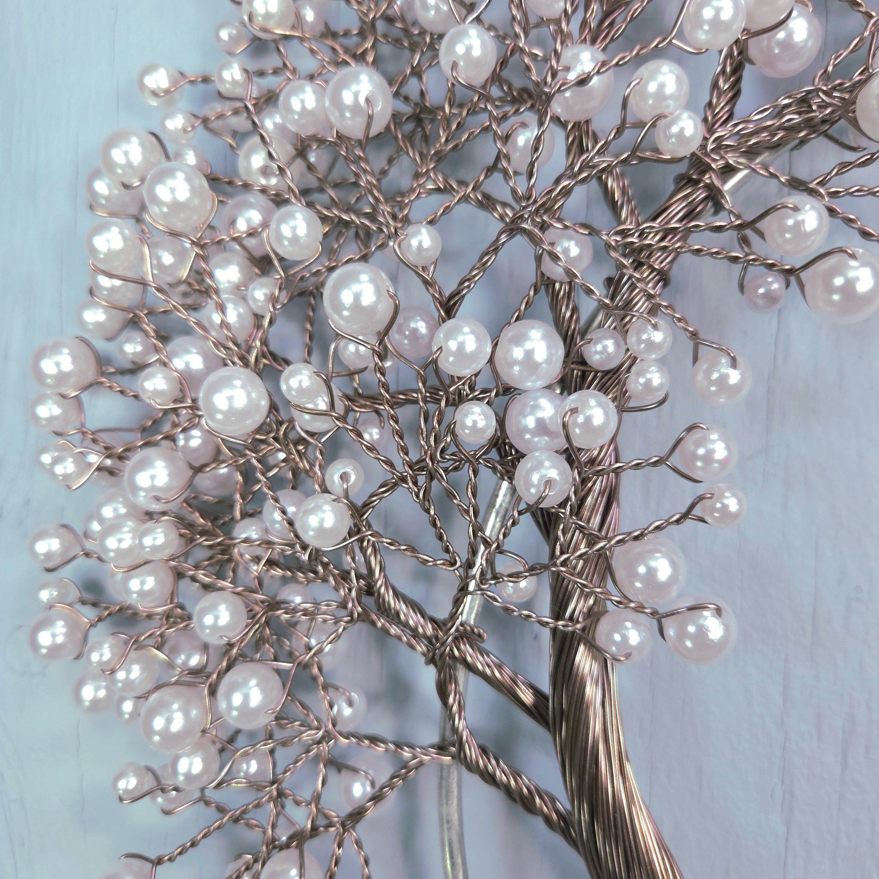 Decorative tree made of branches and pearls on a light blue background