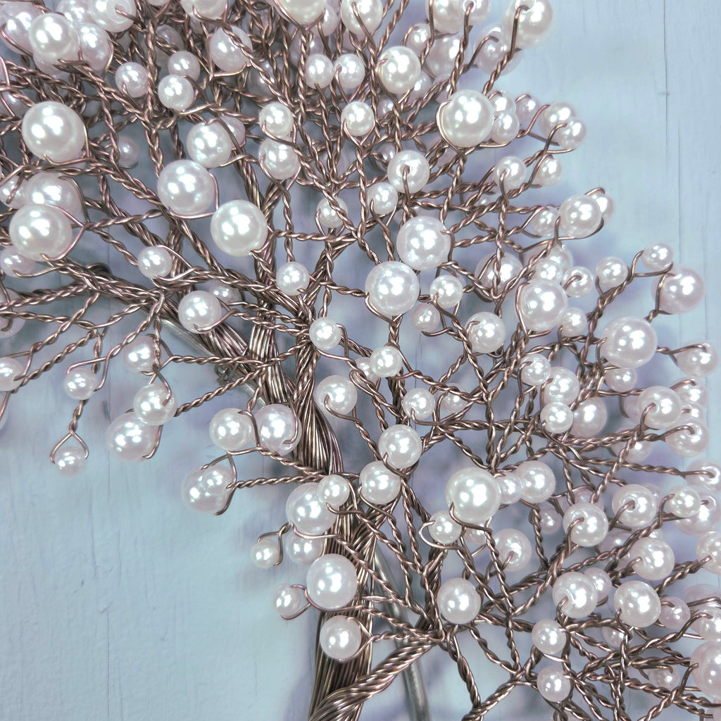 Decorative branch with white beads against a light blue background