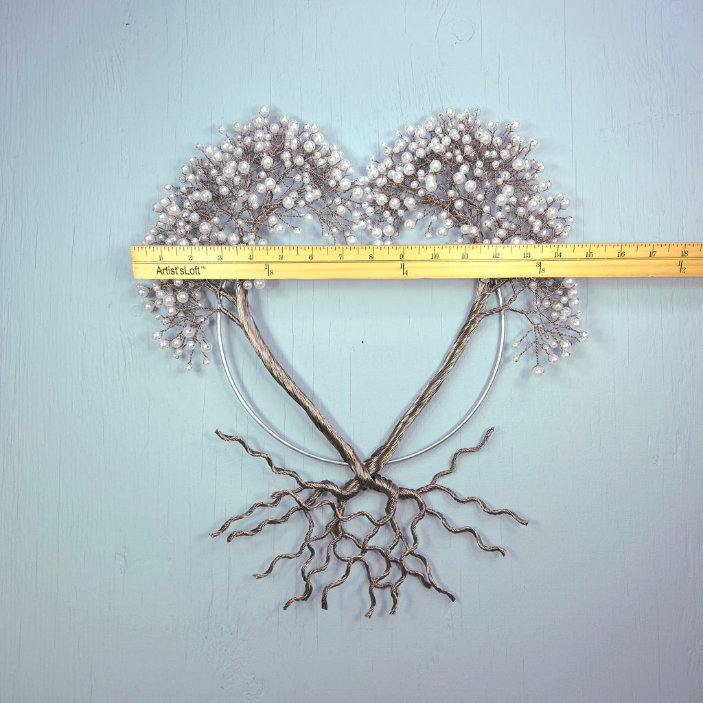 Decorative heart-shaped arrangement with branches and berries on a light blue background, measured by a ruler.