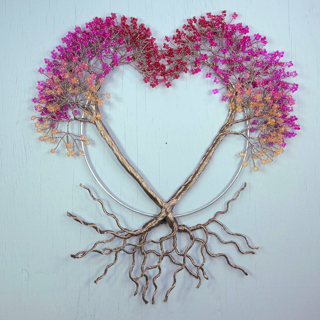 Heart-shaped wreath with pink flowers and bare branches on a light blue background