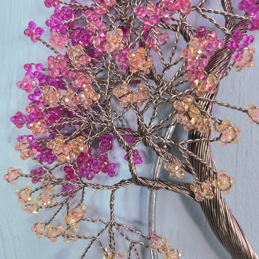 Decorative wall art with pink and orange beaded flowers on a light blue background