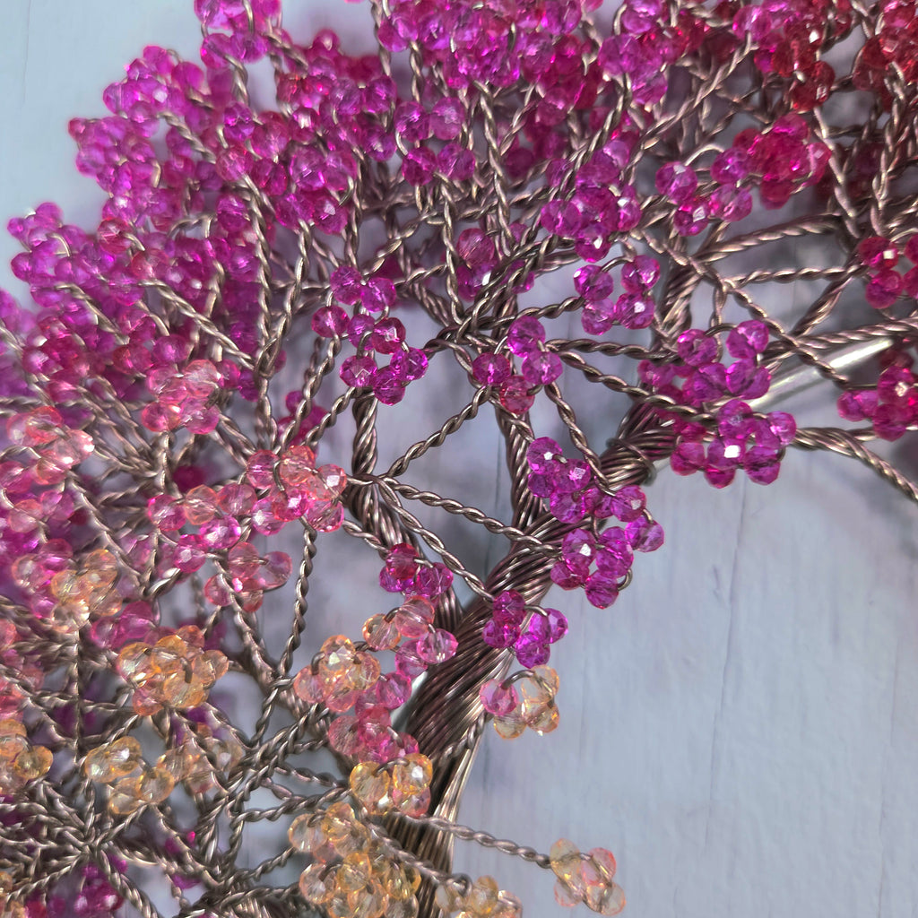 Decorative branch with pink and orange beads on a light blue background
