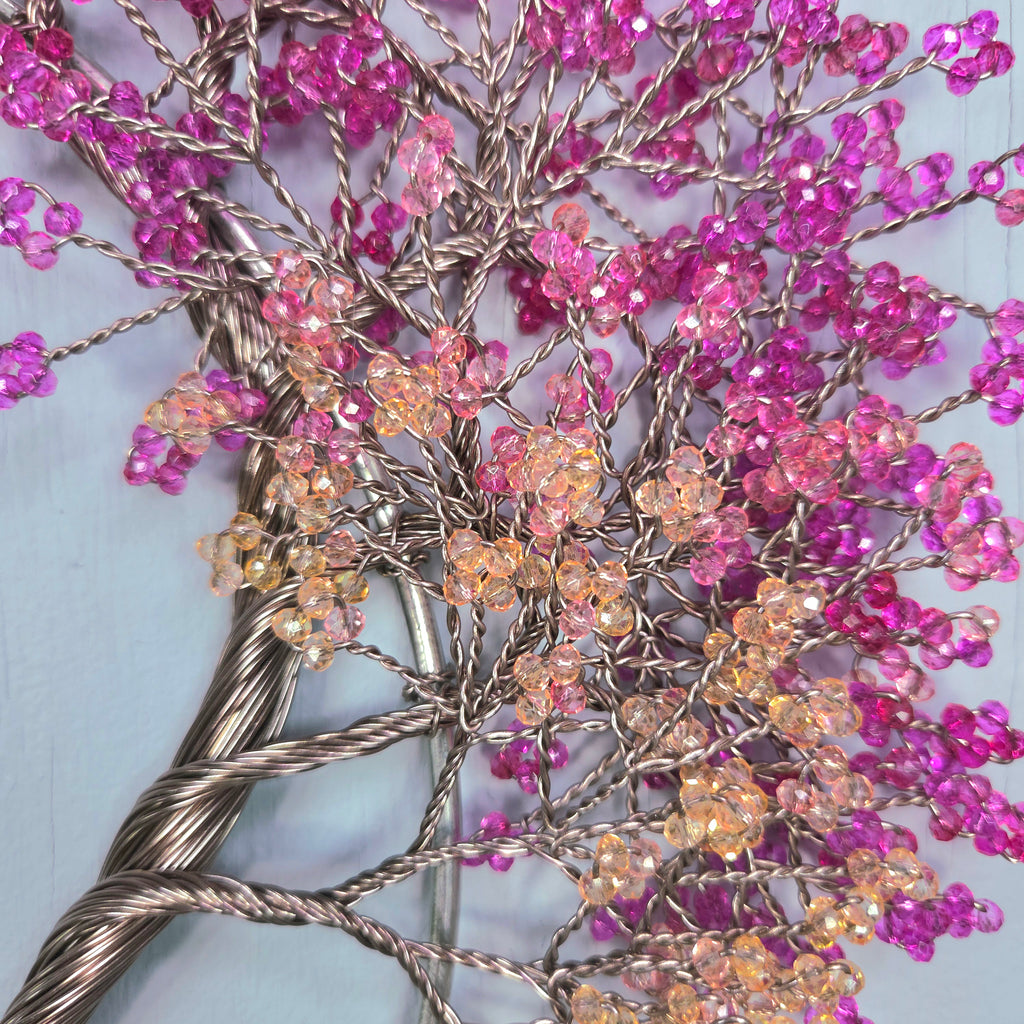 Decorative branch with pink and purple beads on a light blue background