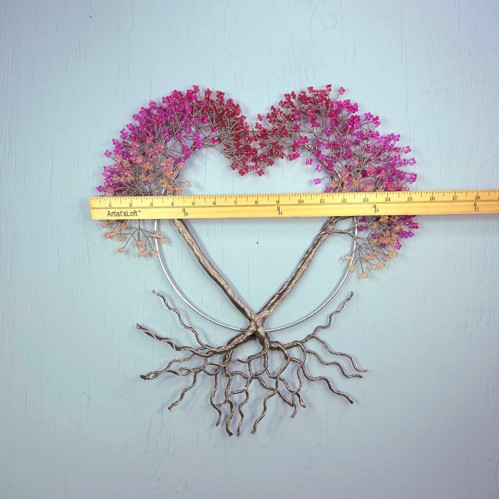 Heart-shaped wall art with pink flowers and branches, measured against a ruler on a light blue background.