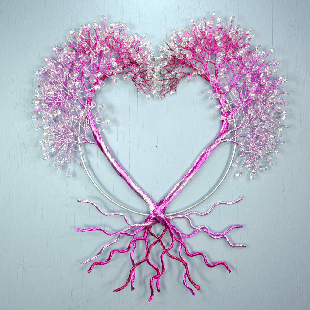 Heart-shaped decoration with pink branches and flowers on a light gray background
