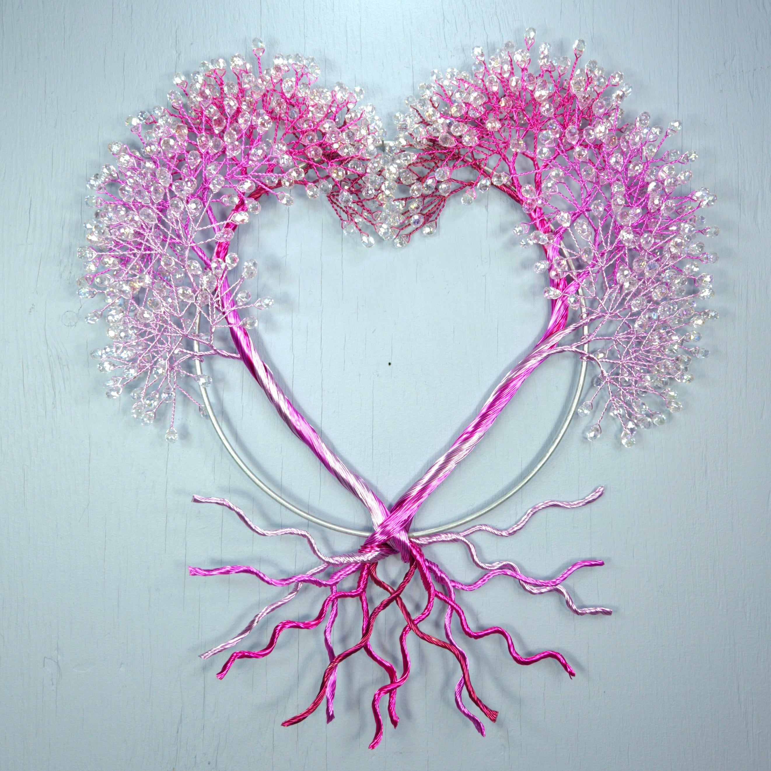 Heart-shaped decoration with pink branches and flowers on a light gray background
