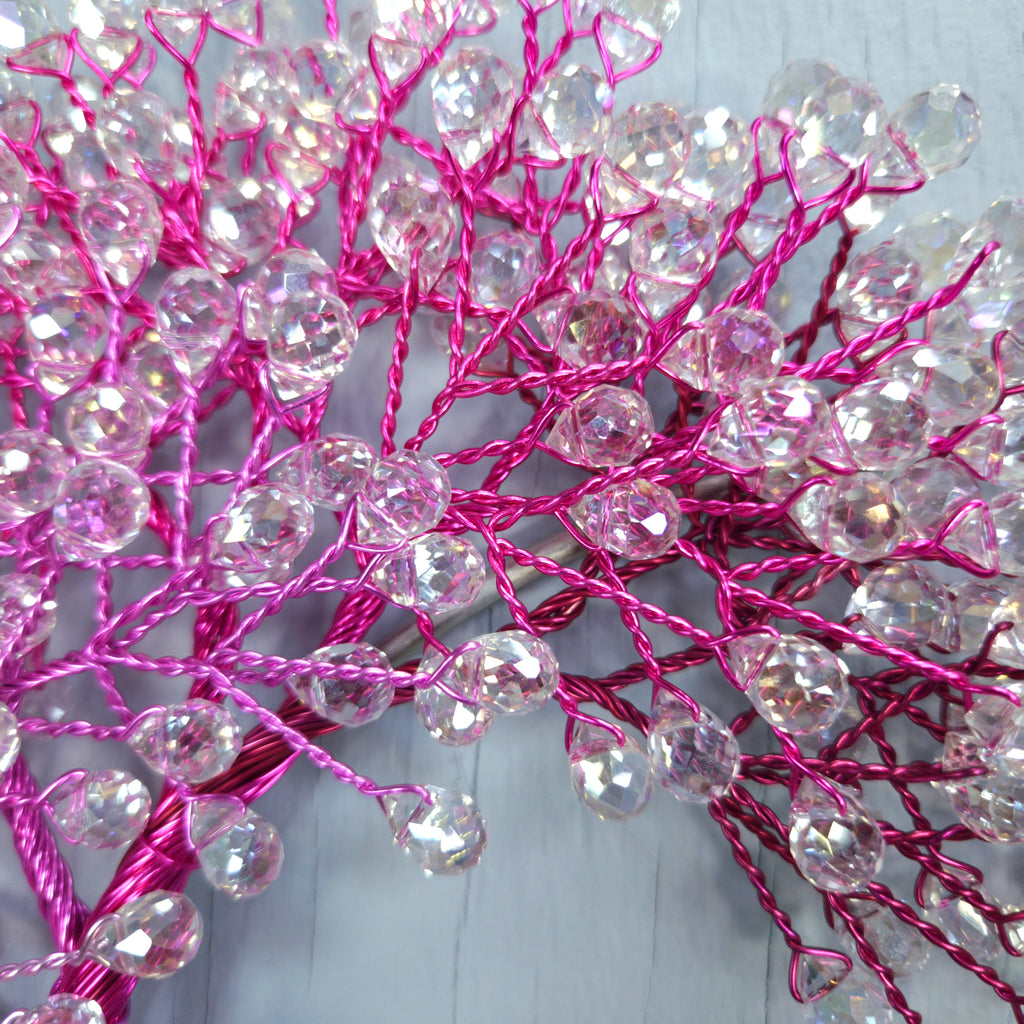 Decorative branch with pink wires and clear beads on a white background