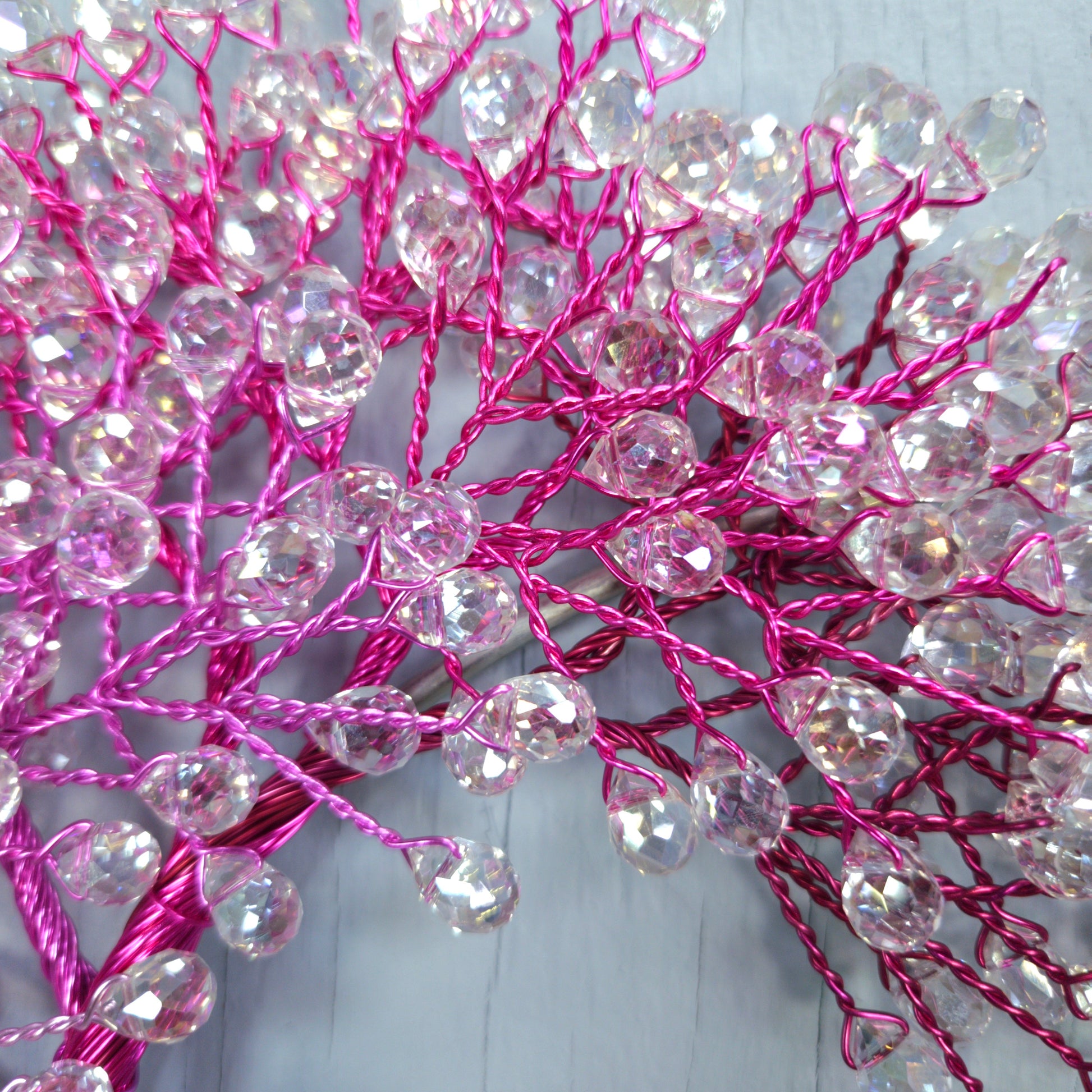 Decorative branch with pink wires and clear beads on a white background
