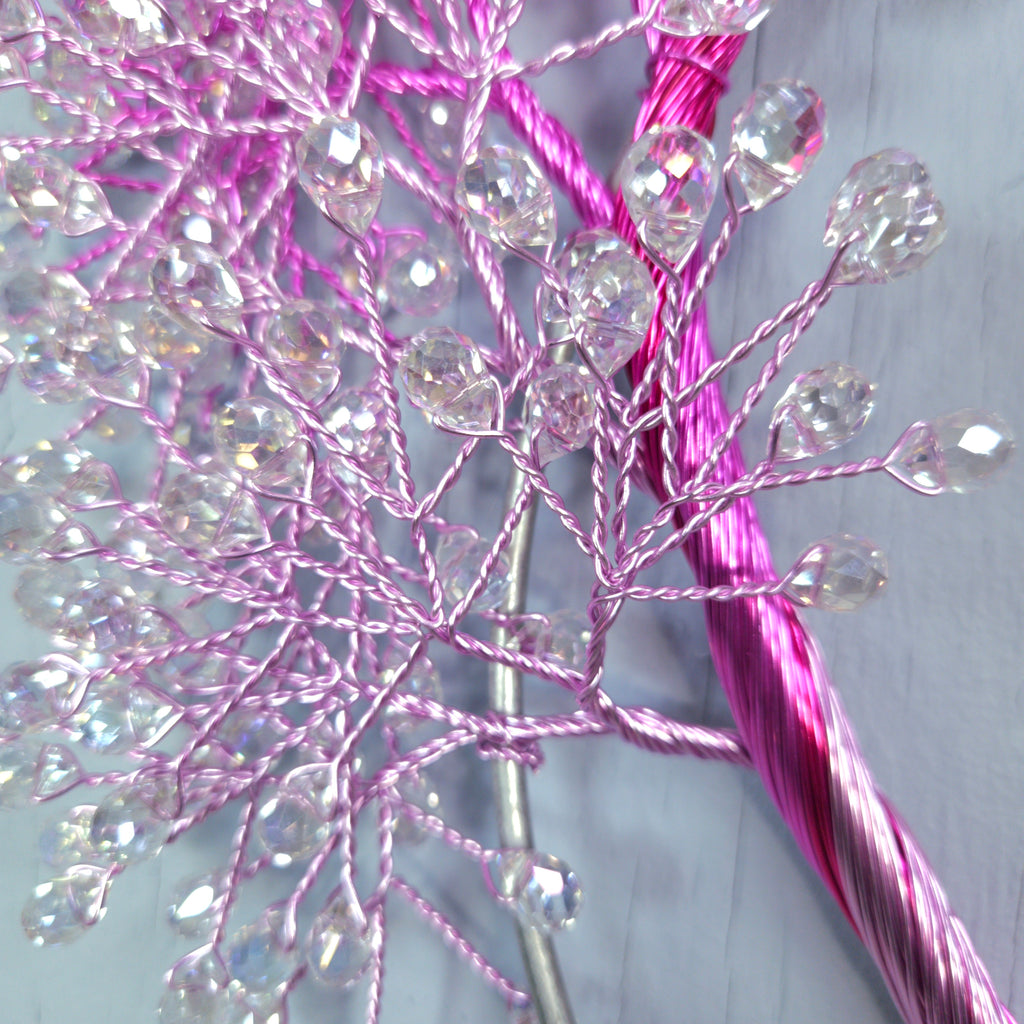 Decorative branch with pink and clear beads on a light gray background