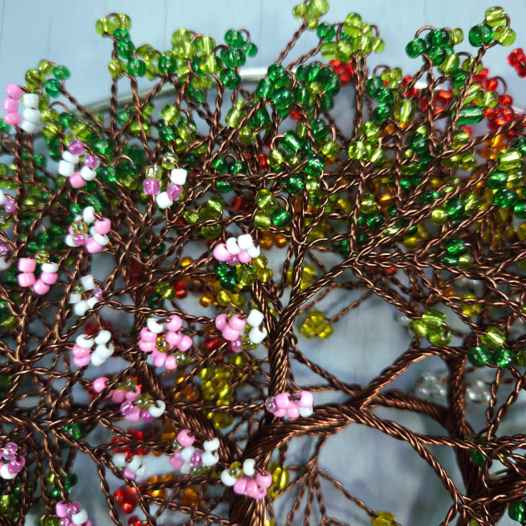 Decorative wall art with beaded branches and flowers on a textured surface