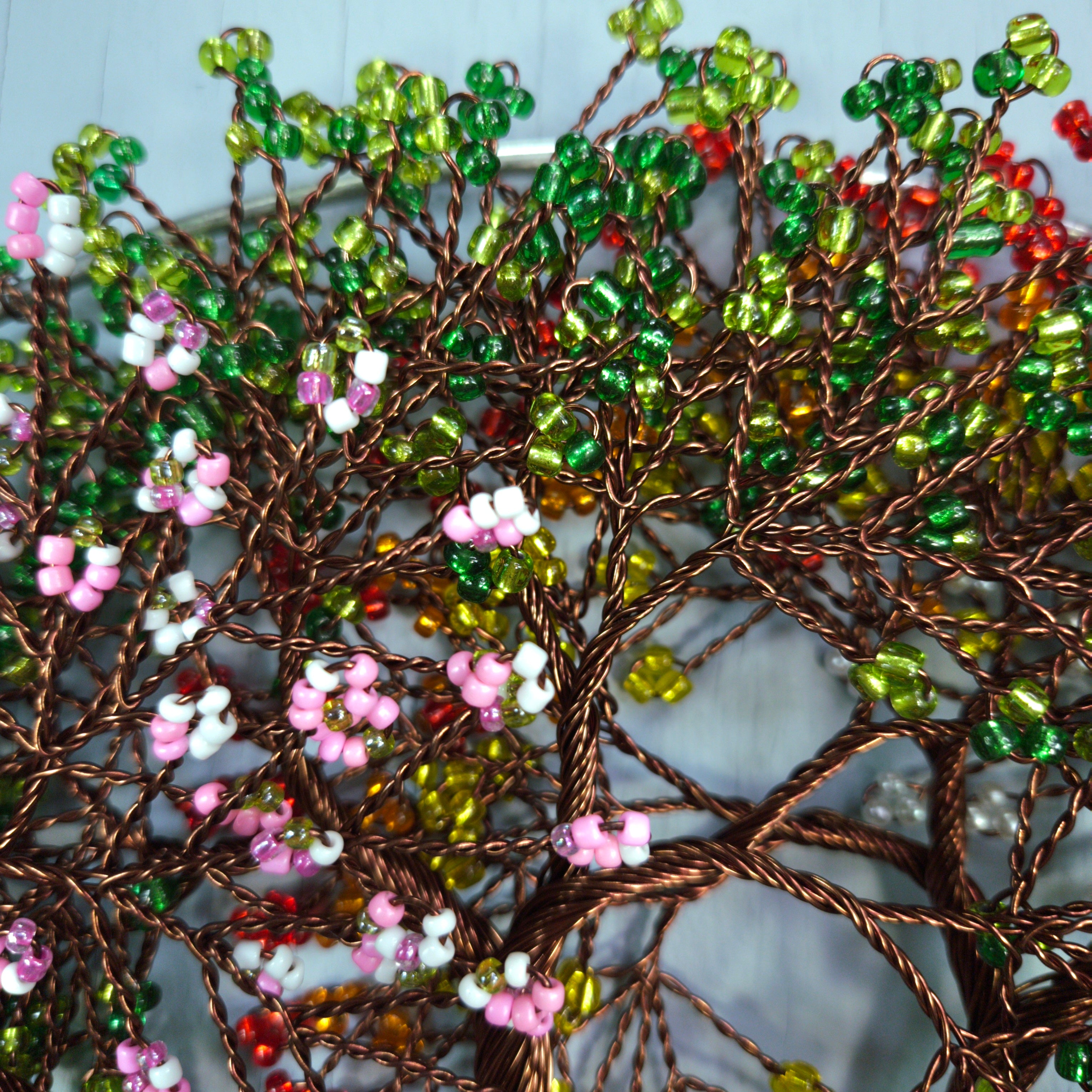 Decorative wall art with beaded branches and flowers on a textured surface