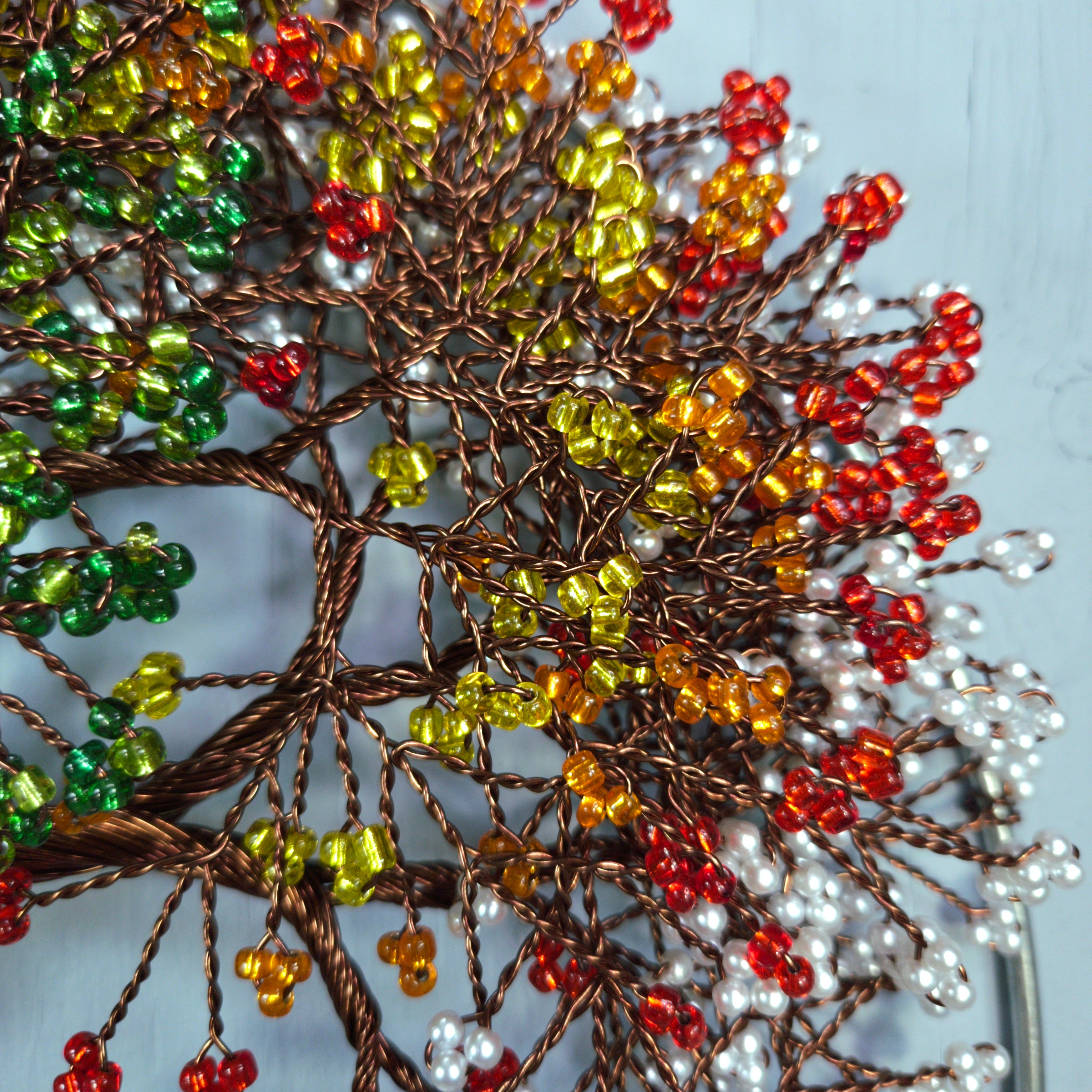 Decorative tree branch with multicolored beads on a light blue background