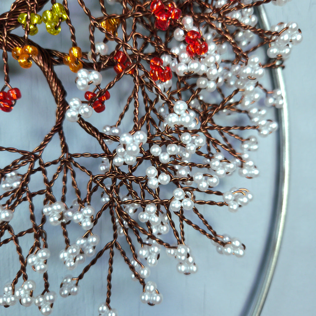 Decorative wreath with brown wire branches, white beads, and red berries on a light blue background.