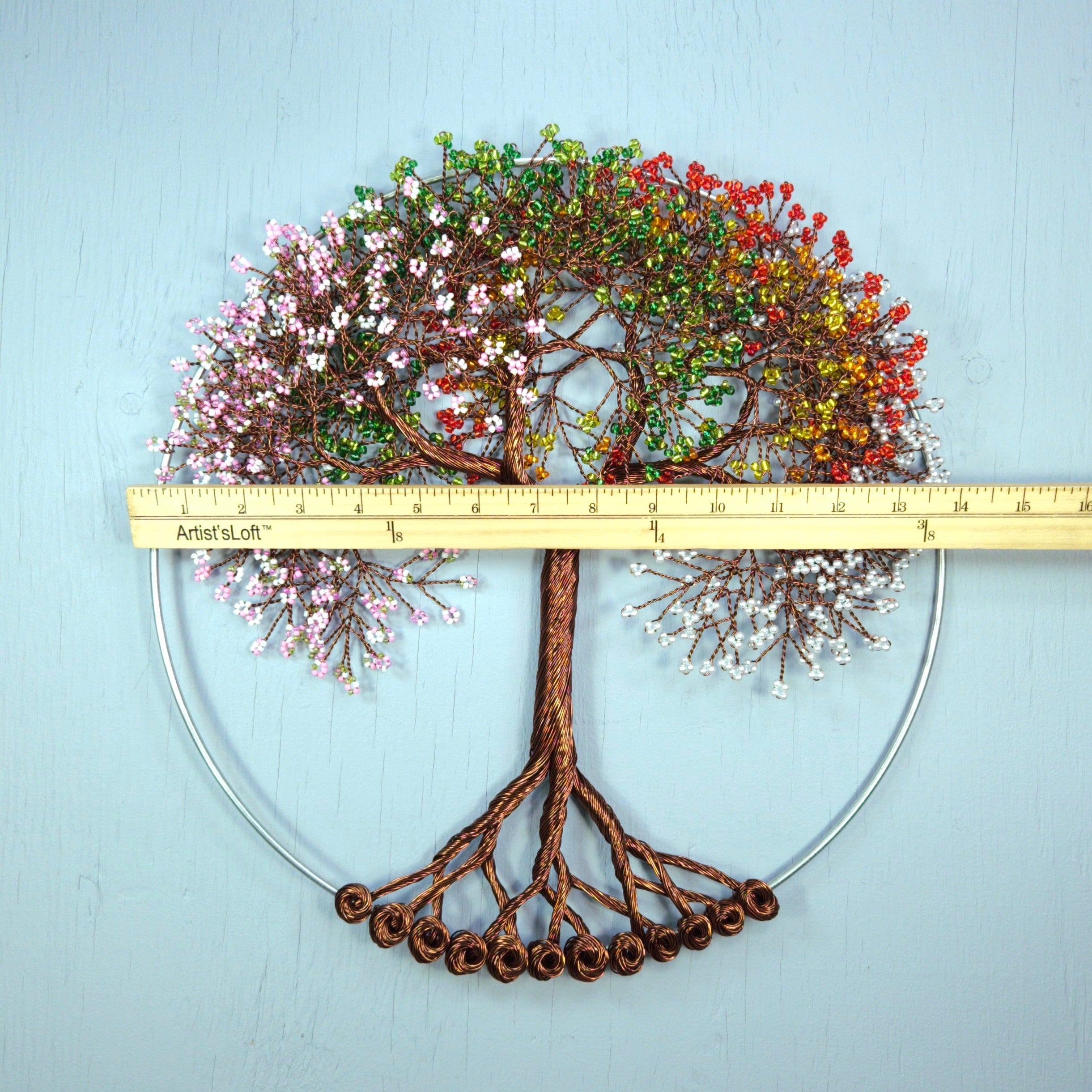 Decorative wall art of a tree with colorful leaves and roots on a light blue background.