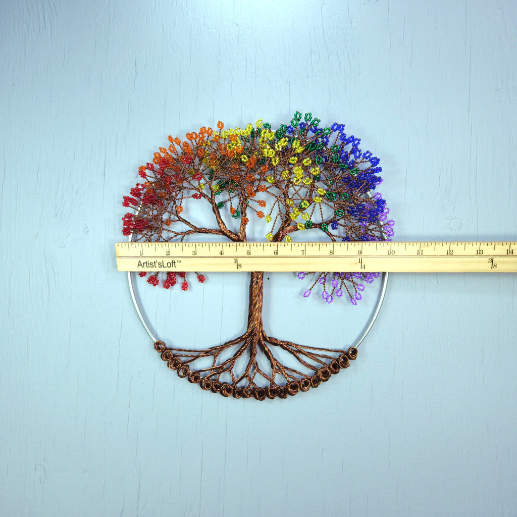 Decorative tree wall art with rainbow-colored leaves on a light blue background, measured by a ruler.