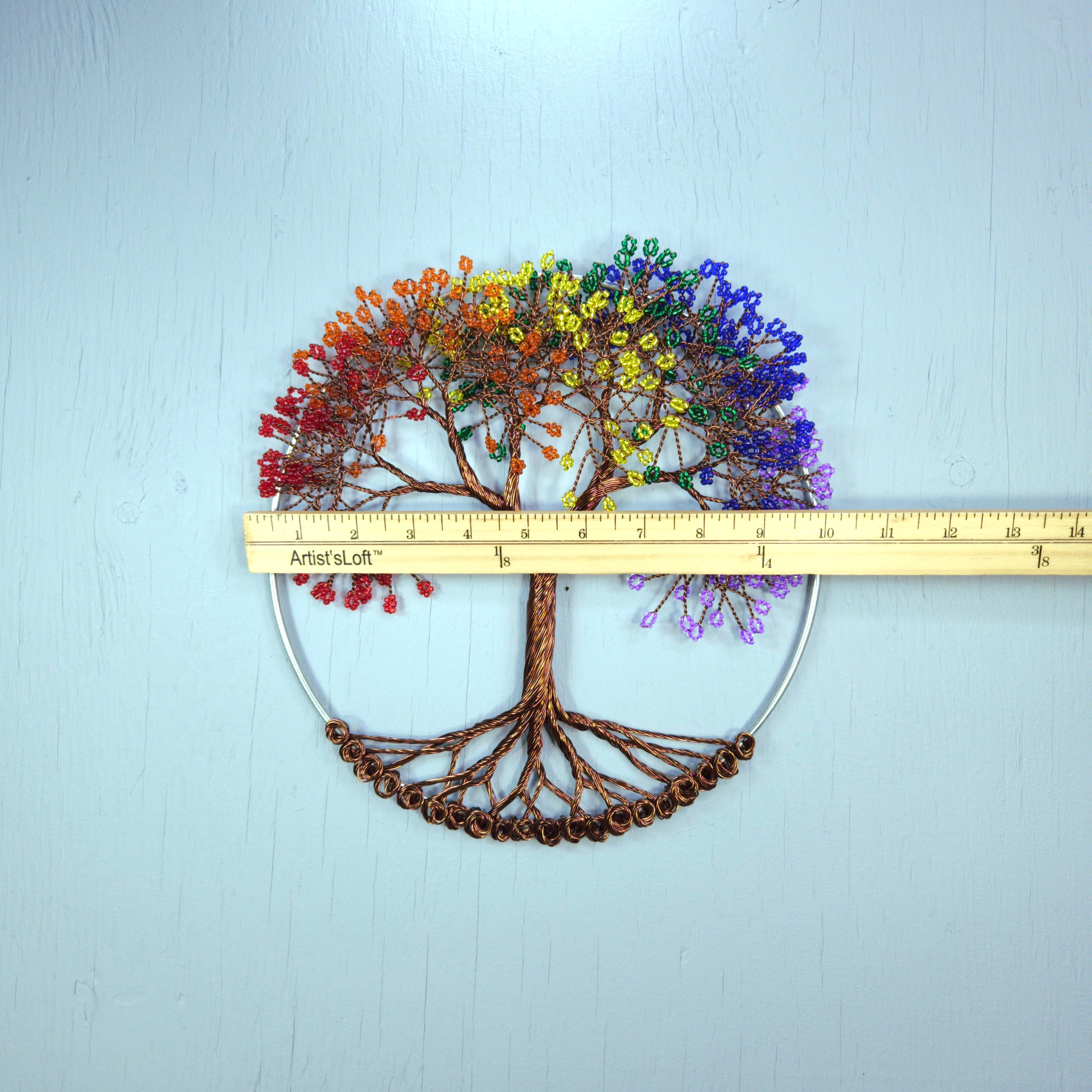 Decorative tree wall art with rainbow-colored leaves on a light blue background, measured by a ruler.
