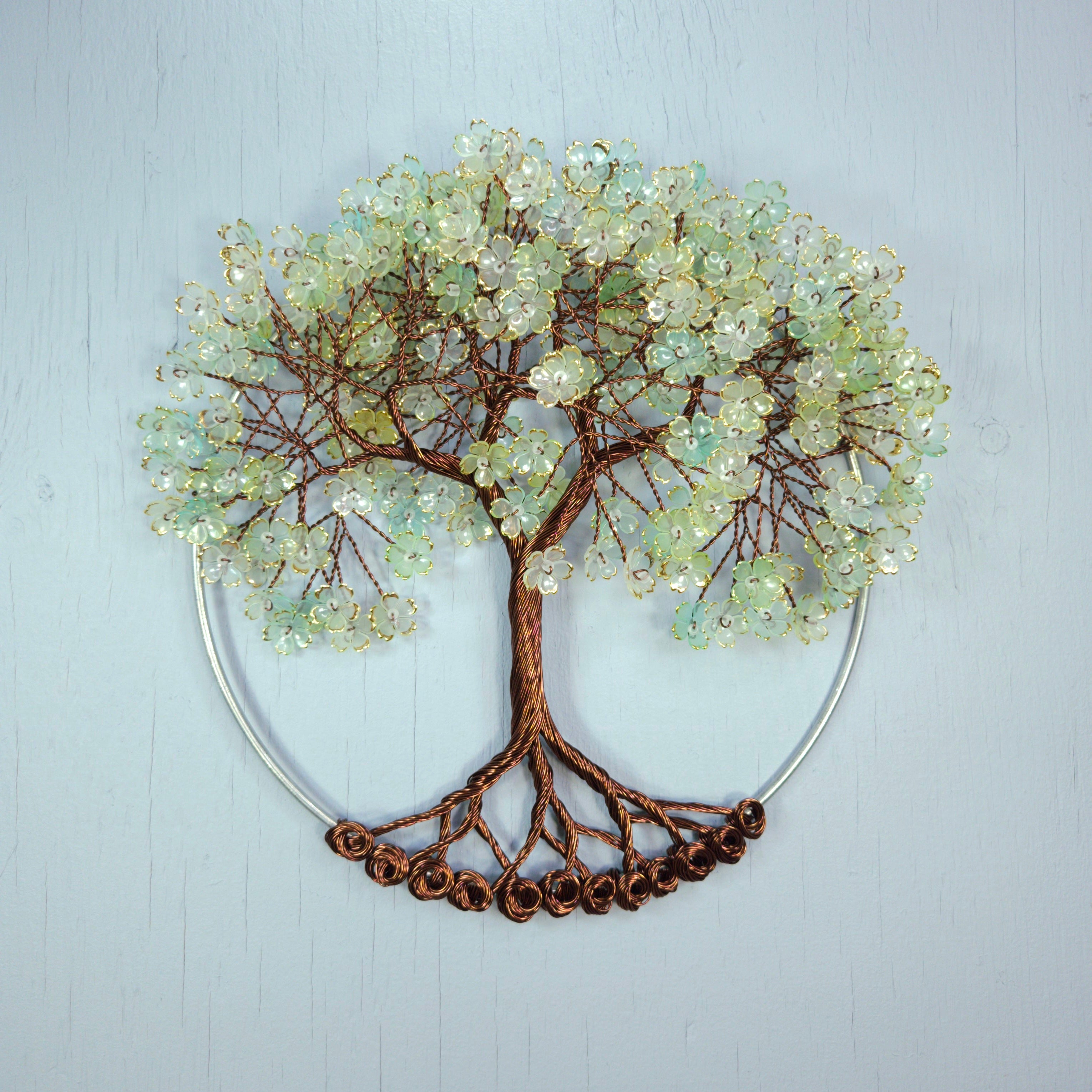 Decorative wall art of a tree with bead-like leaves on a light blue background
