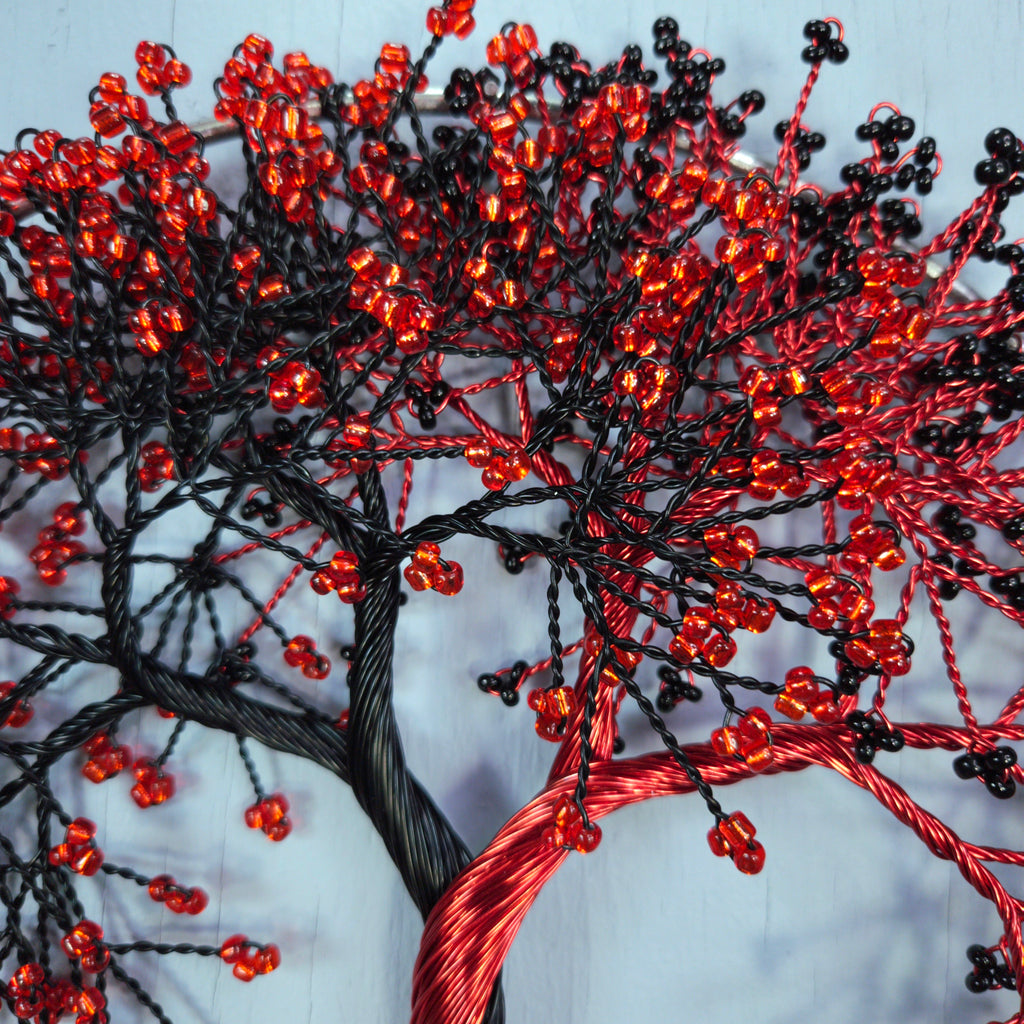 Decorative tree made of red and black beaded branches on a white background