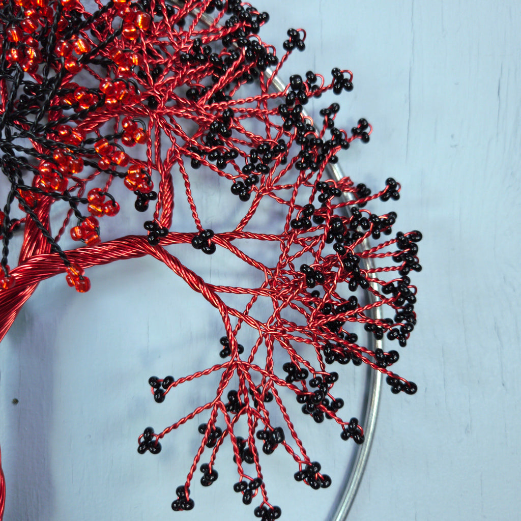 Red and black beaded branches on a light blue background