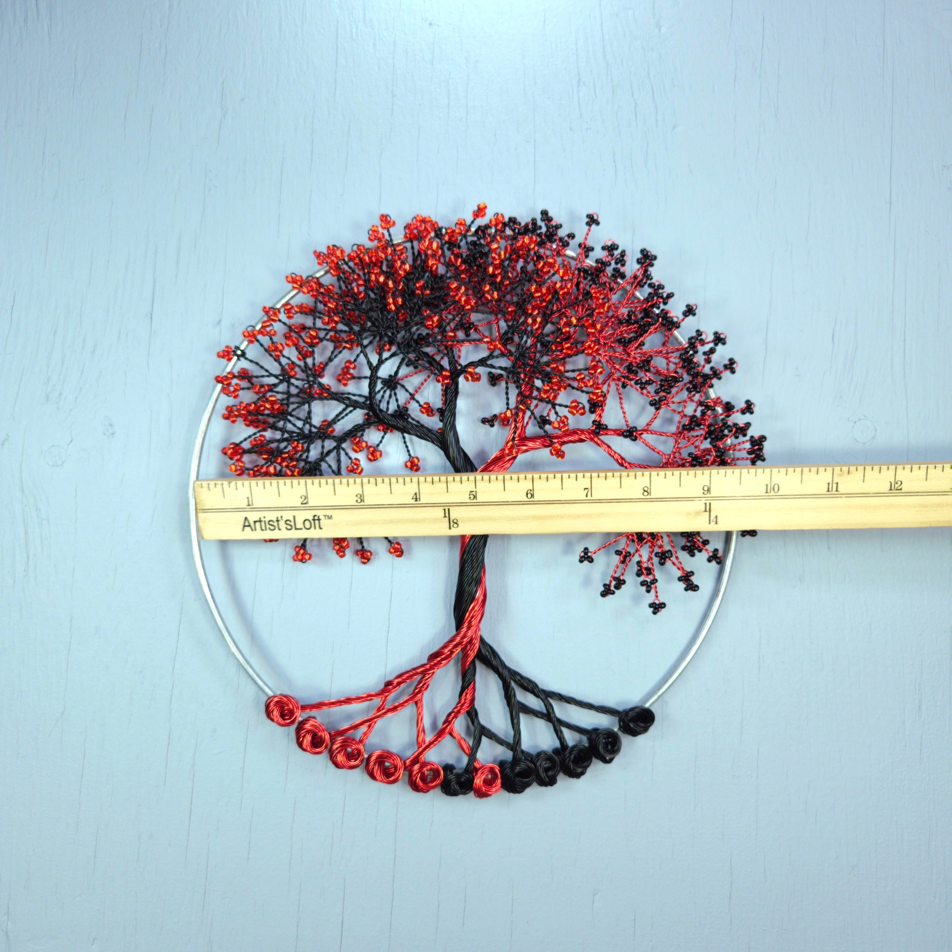 Decorative tree wall art with red and black branches on a light blue background, measured by a ruler.