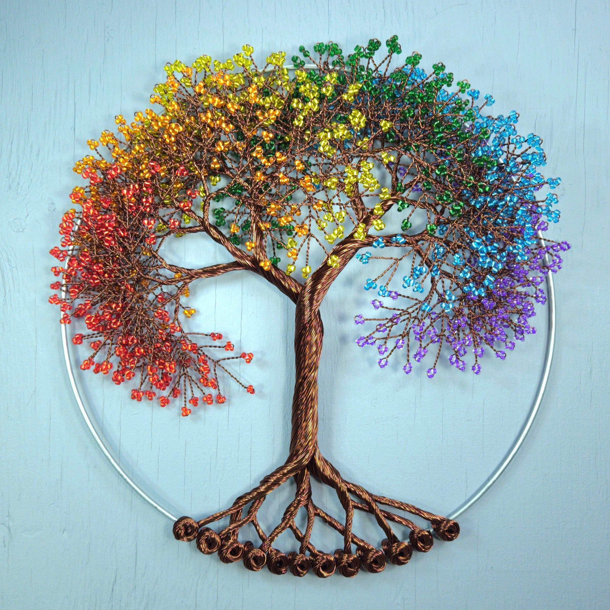 Colorful tree wall art with rainbow leaves on a light blue background