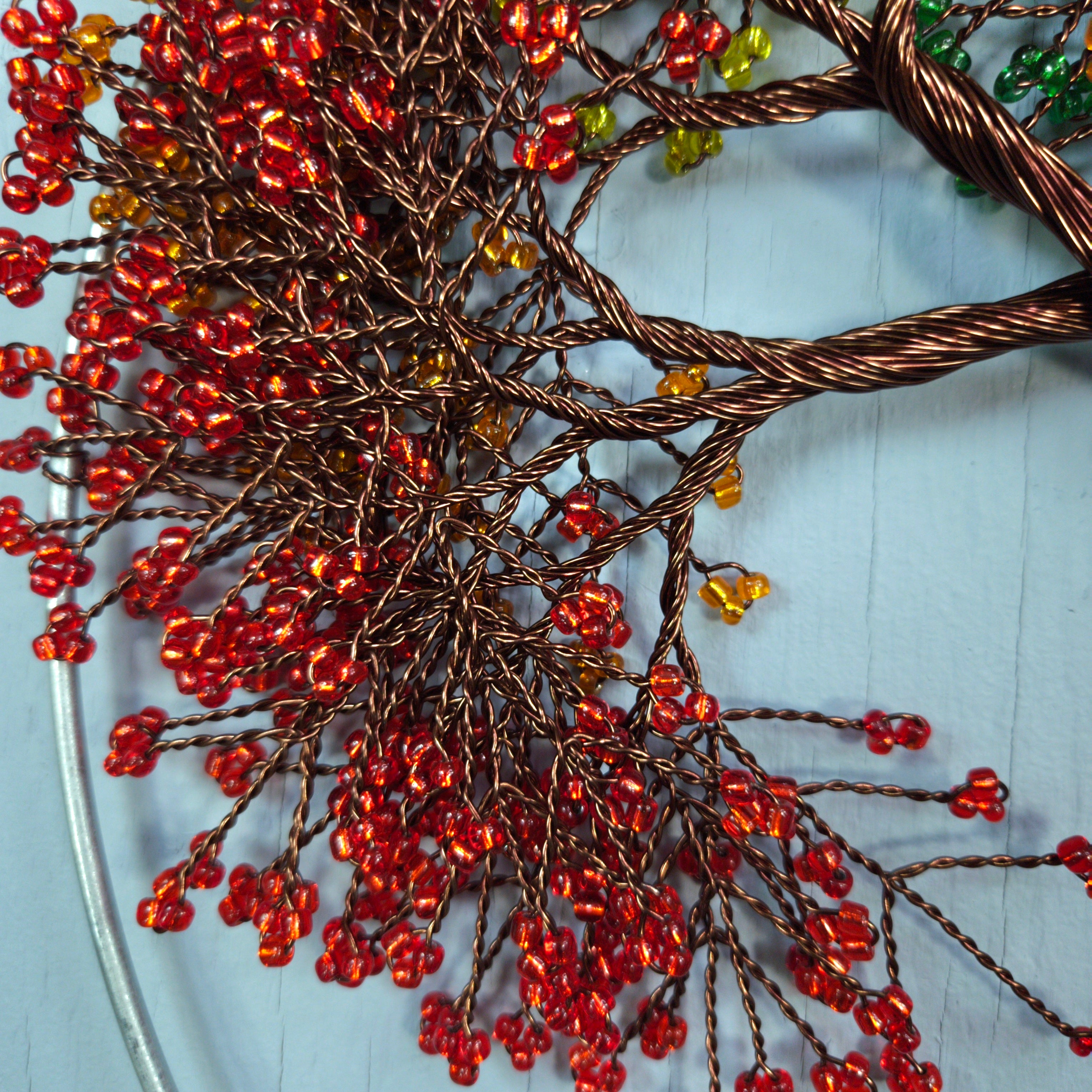 Decorative branch with red and gold beads on a light blue background