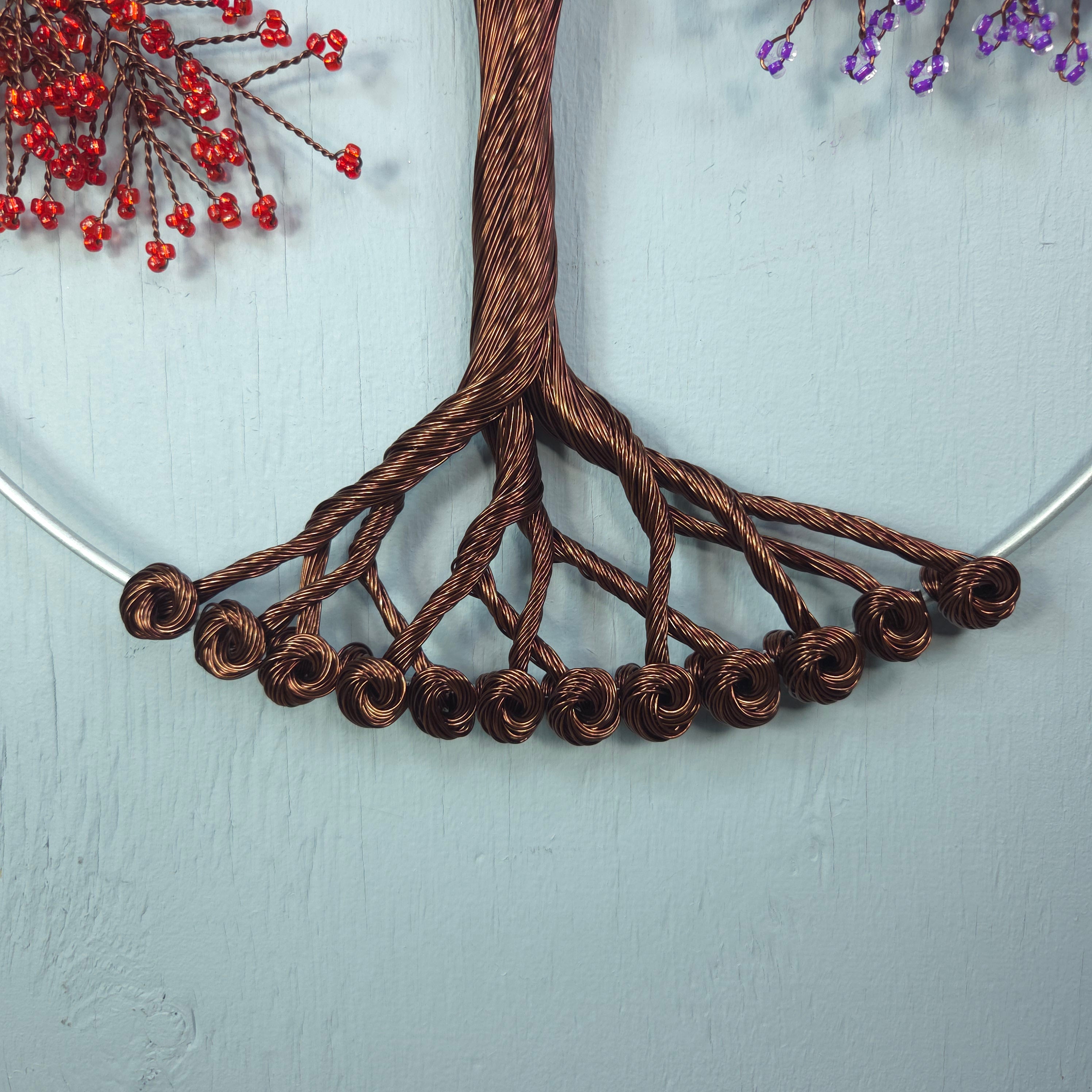 Decorative brown wire tree on a light gray background with red and purple floral elements.