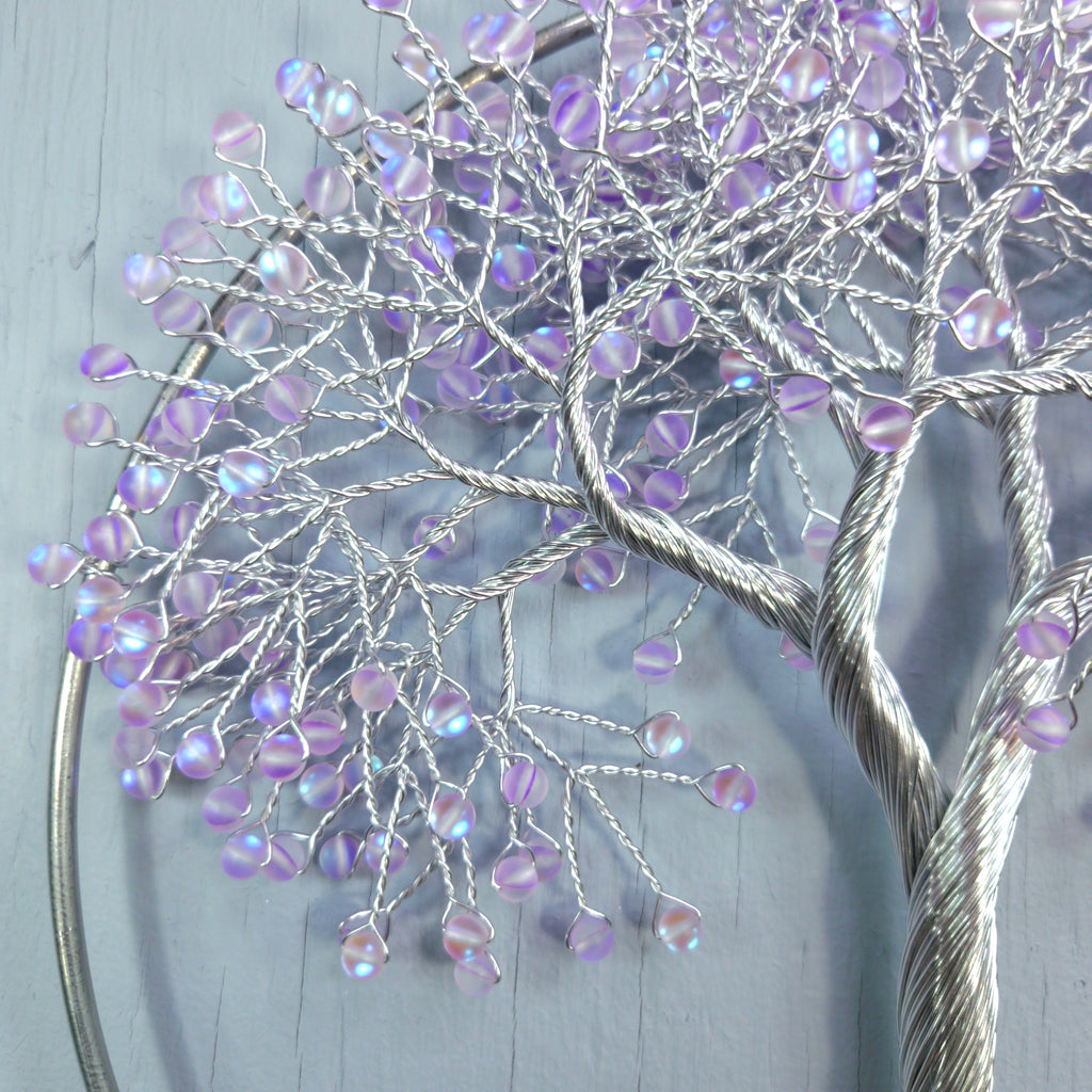 Decorative tree sculpture with purple beads on a light gray background