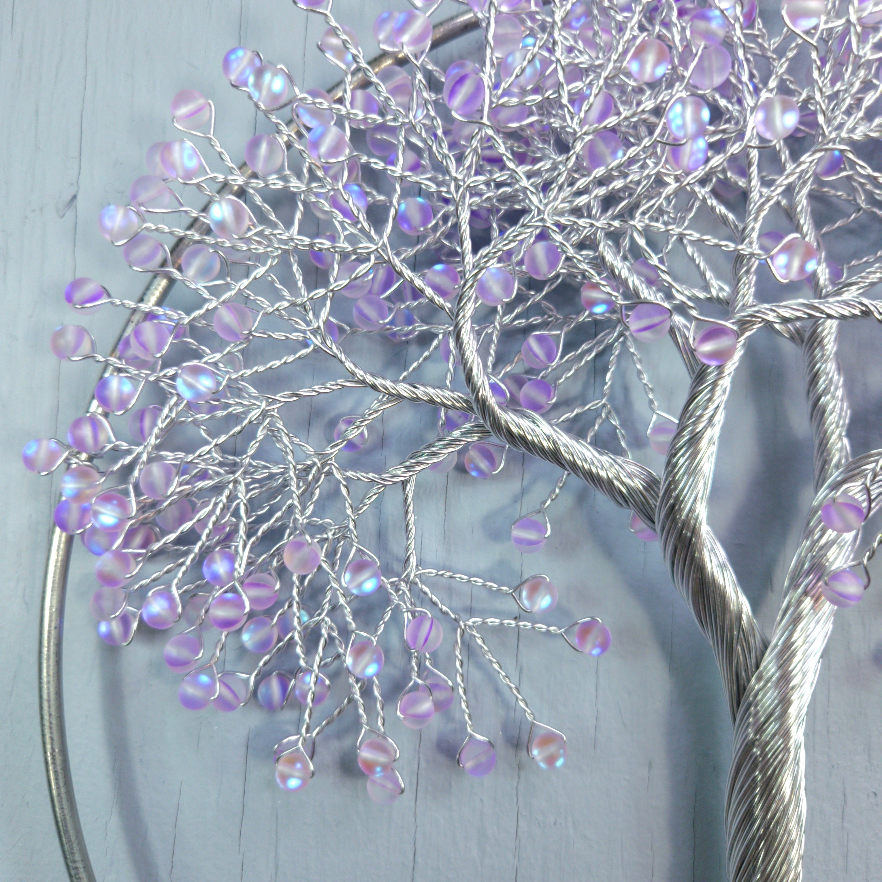 Decorative tree sculpture with purple beads on a light gray background