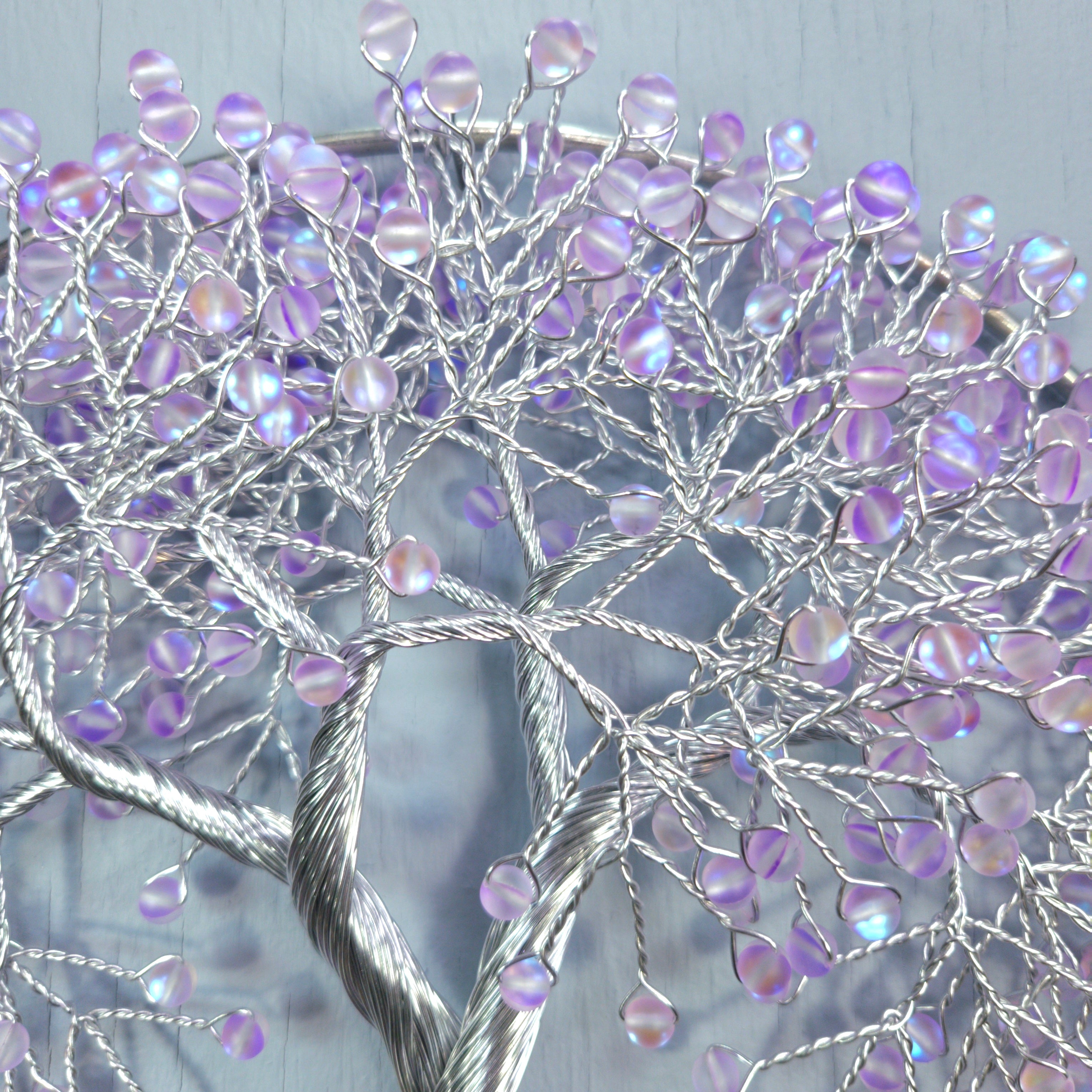 Decorative wall art with a tree design featuring purple beads on a light blue background