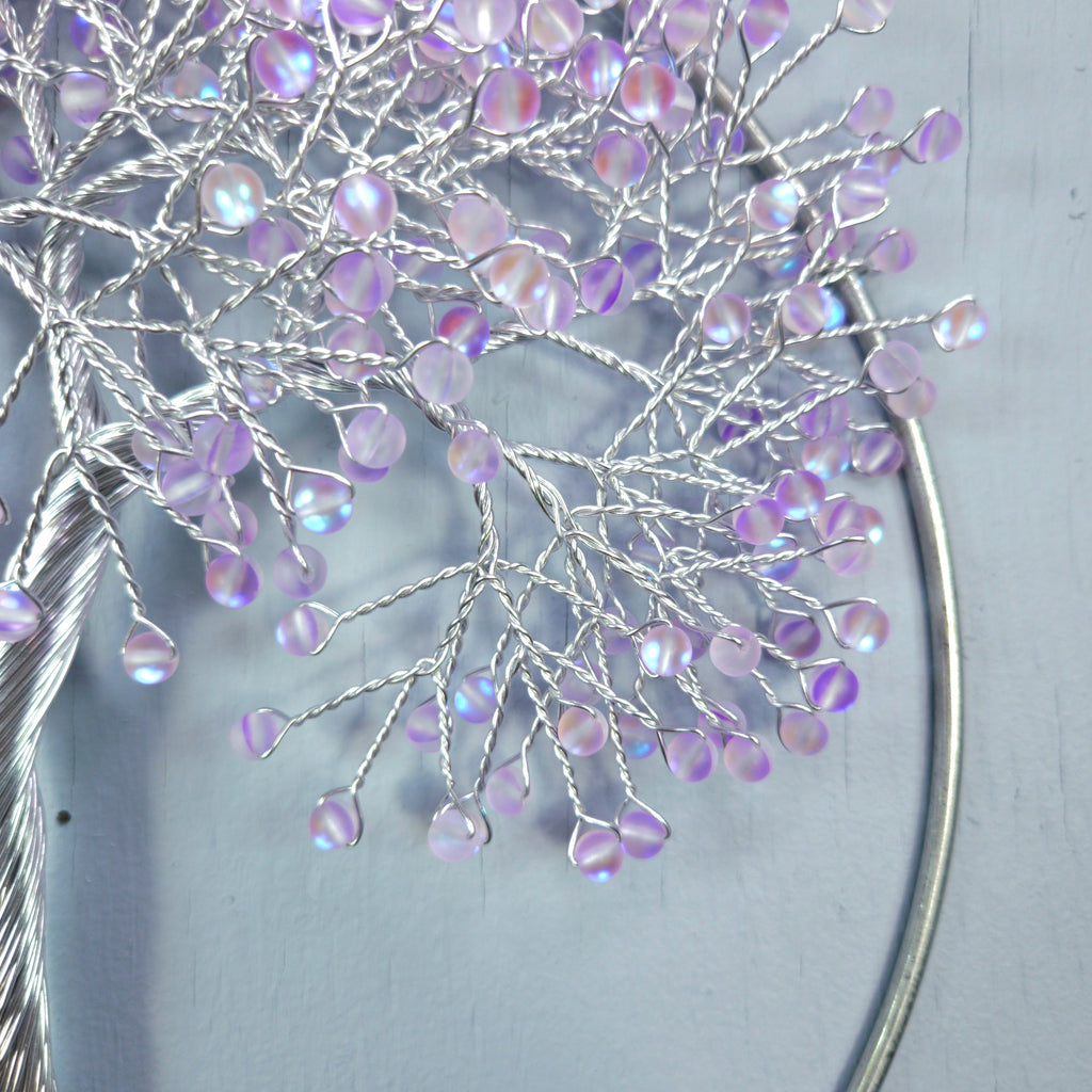 Decorative branch with purple beads on a light gray background
