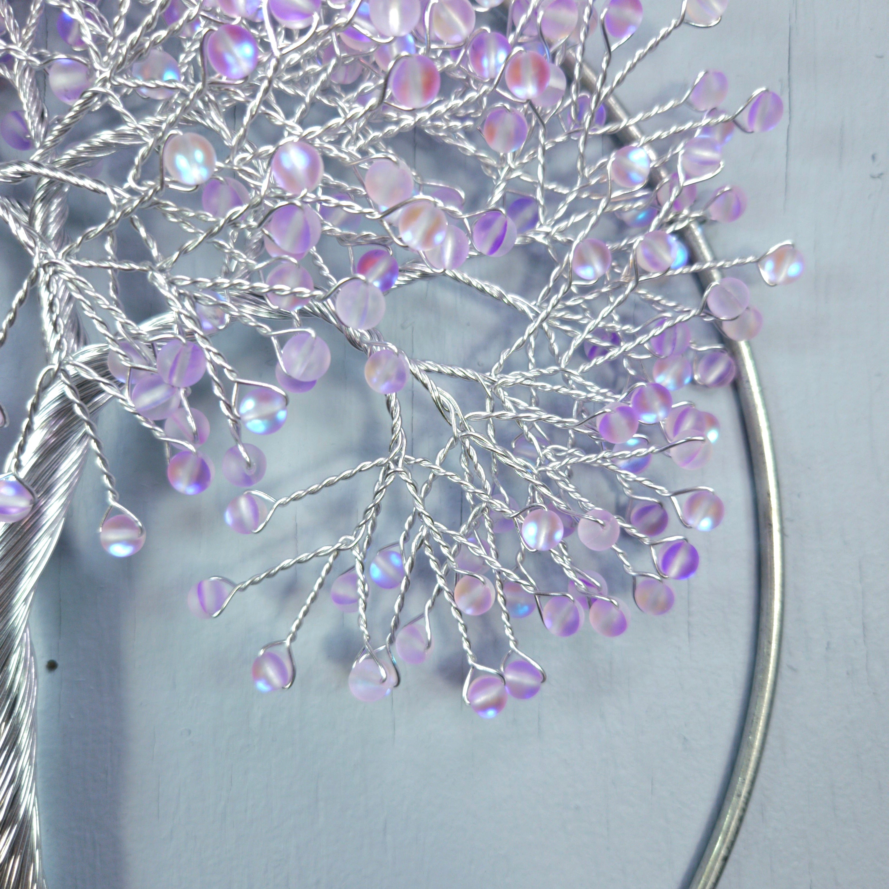 Decorative branch with purple beads on a light gray background