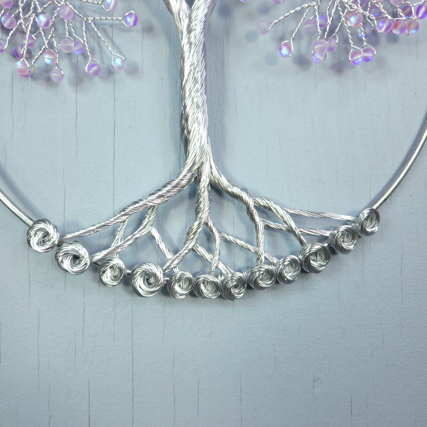 Silver necklace with beaded branches on a light gray background