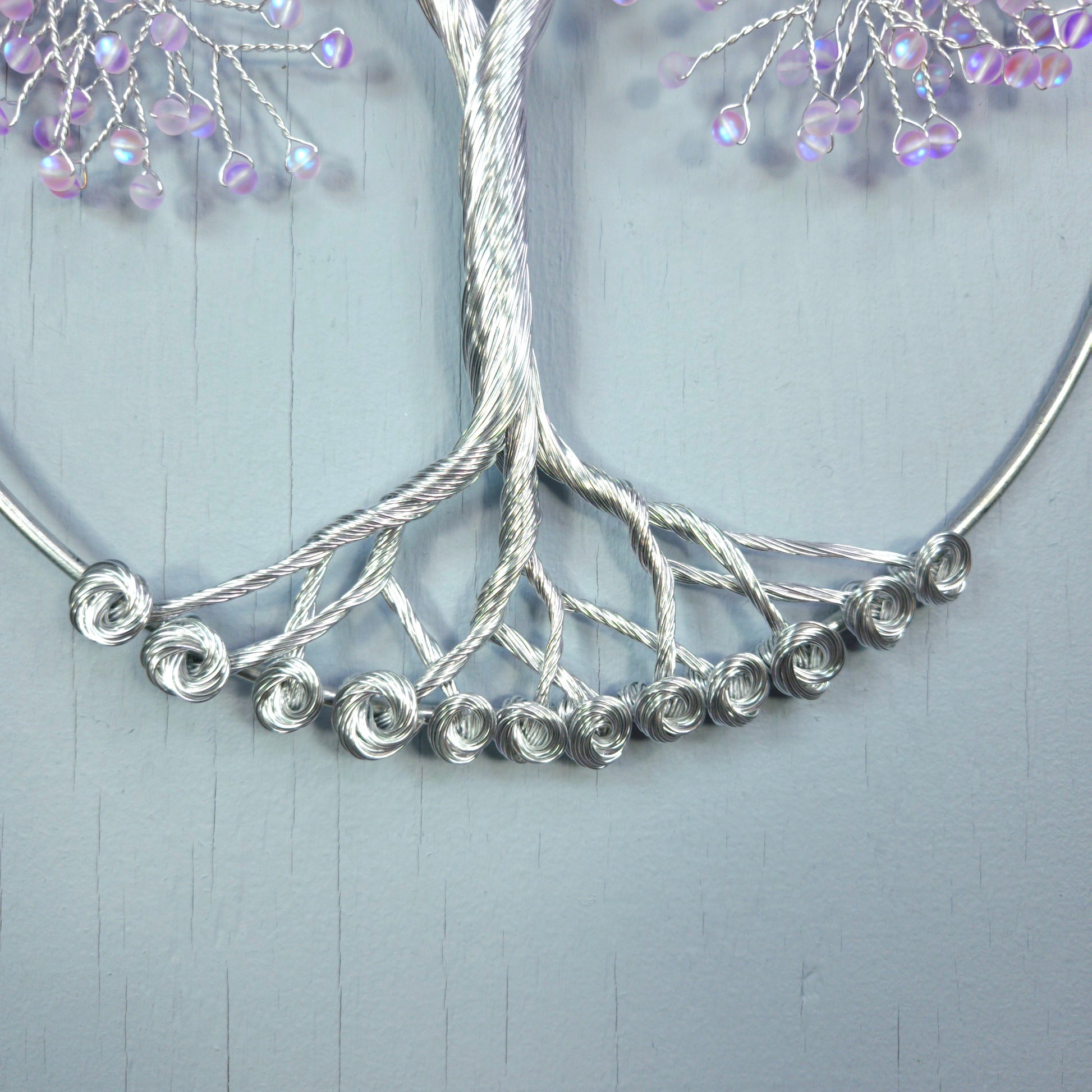 Silver necklace with beaded branches on a light gray background